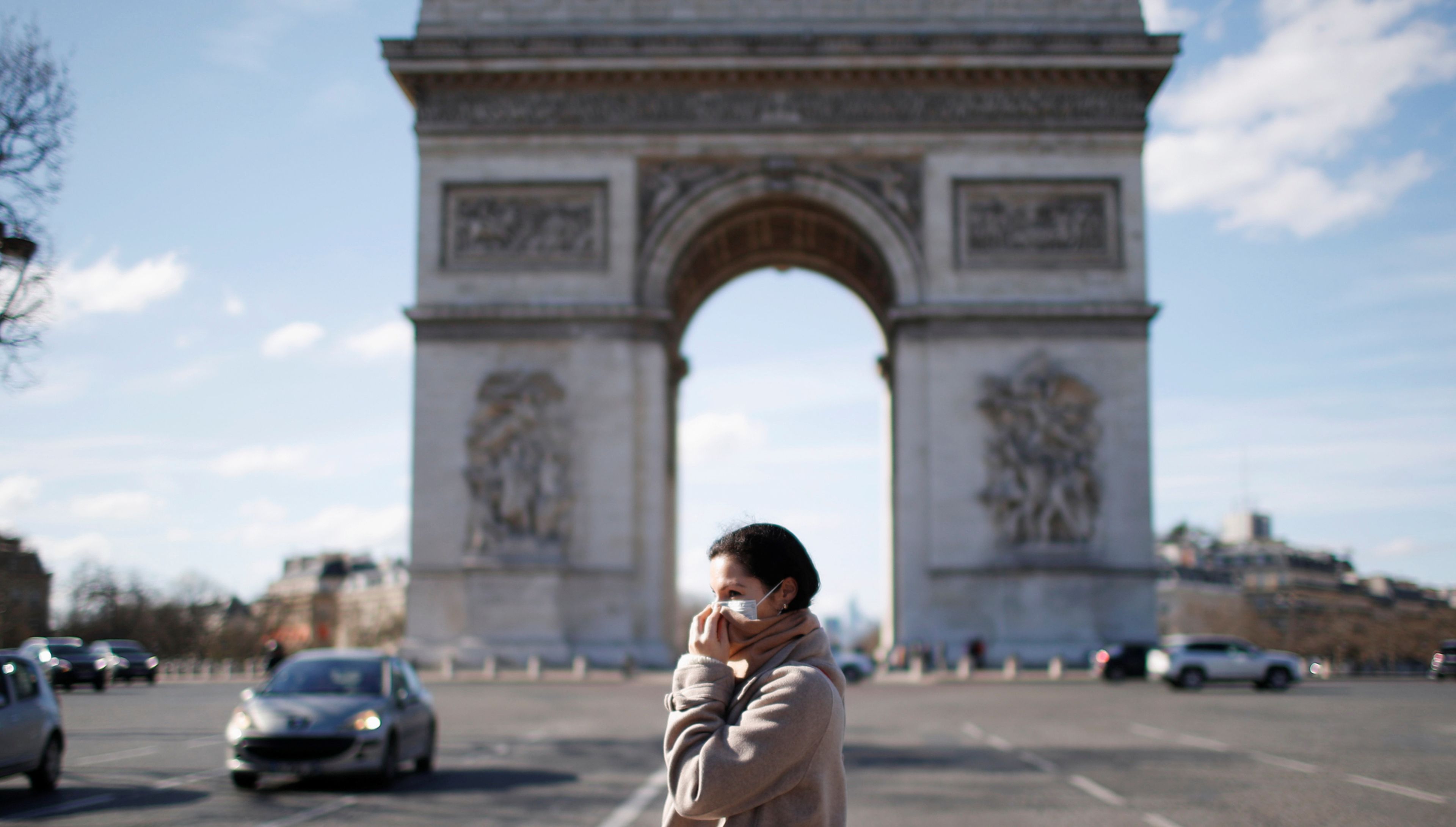 Una mujer con mascarilla pasa ante el Arco del Triunfo de París