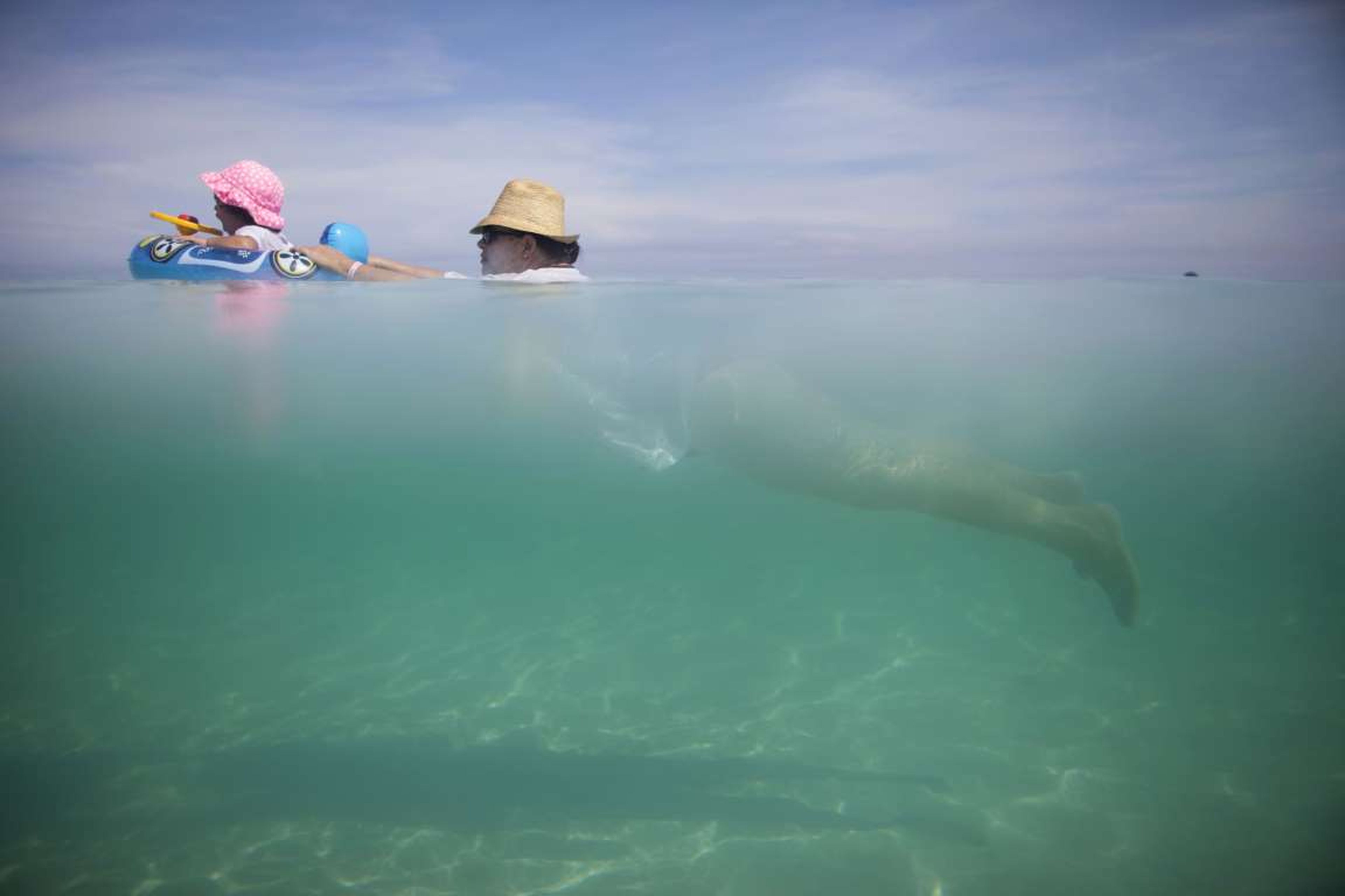 Una mujer nada en la playa con su nieta en Cuba.