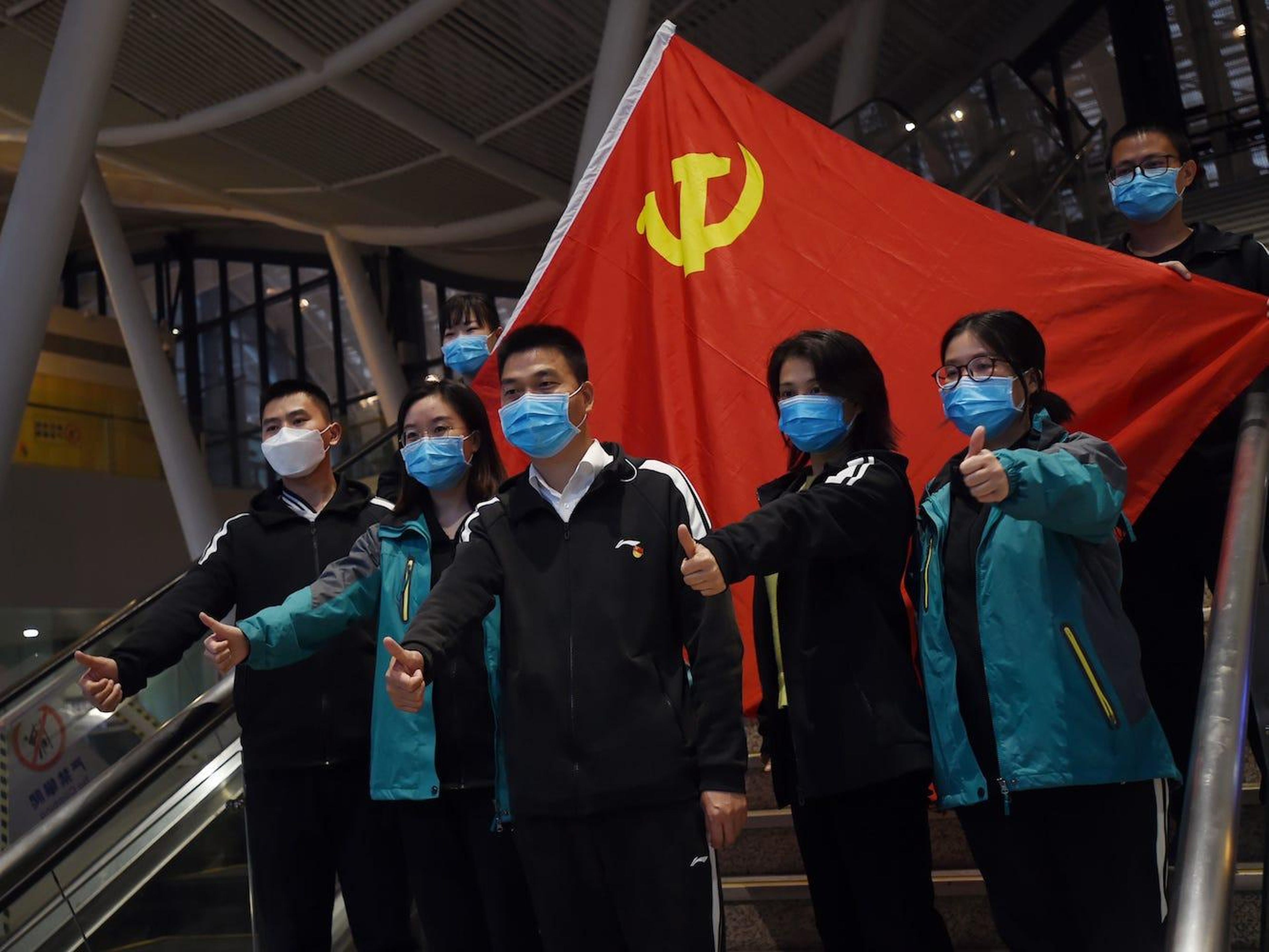 Trabajadores sanitarios de fuera de Wuhan posan para una fotografía con la bandera del partido comunista chino en la estación de tren de la capital de la región antes de rvolver a sus casas, el pasado 17 de marzo de 2020.
