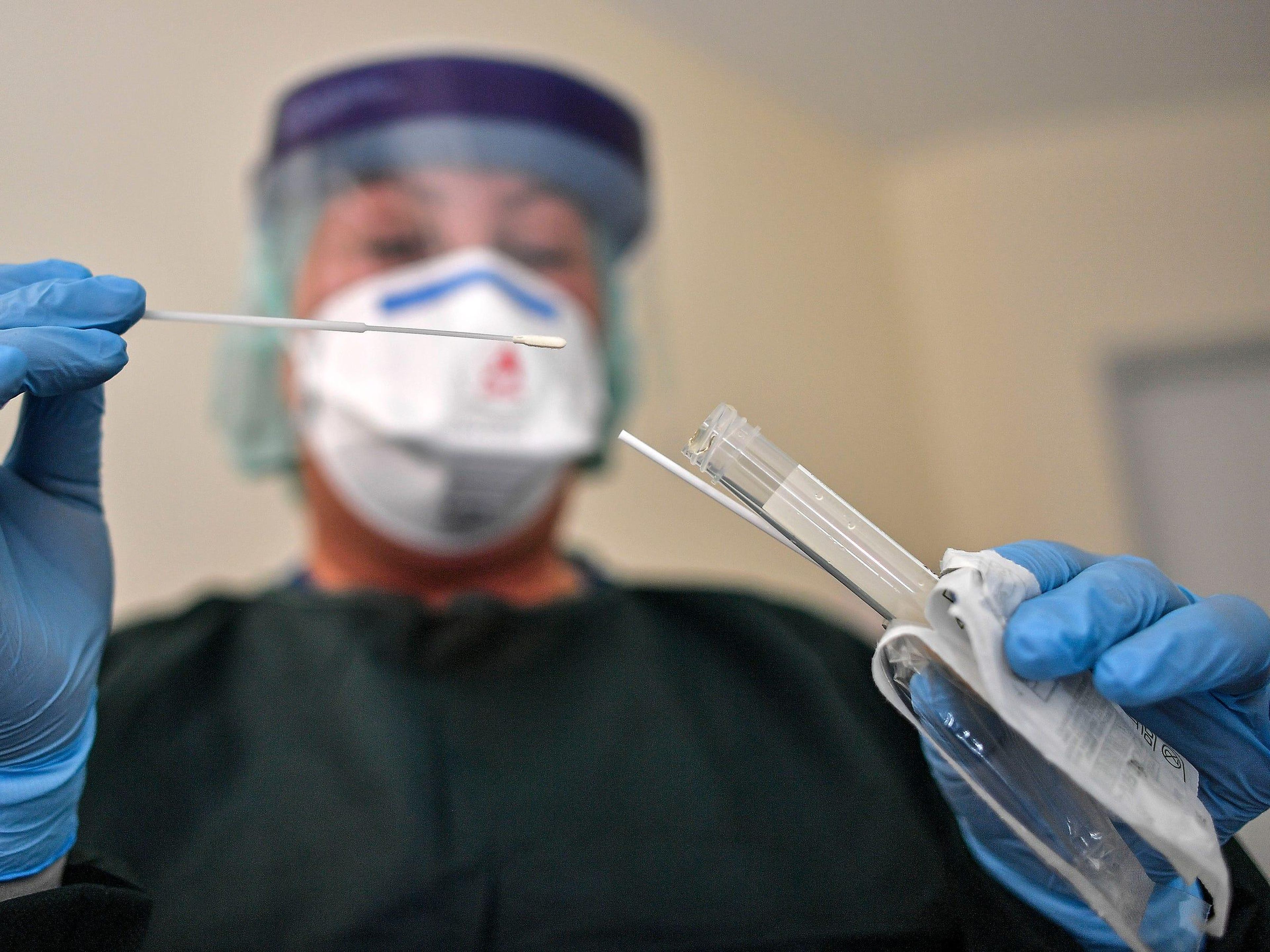 A nurse demonstrates taking a sample for a coronavirus test at the infection station of the university hospital in Essen, Germany, Thursday, March 12, 2020.