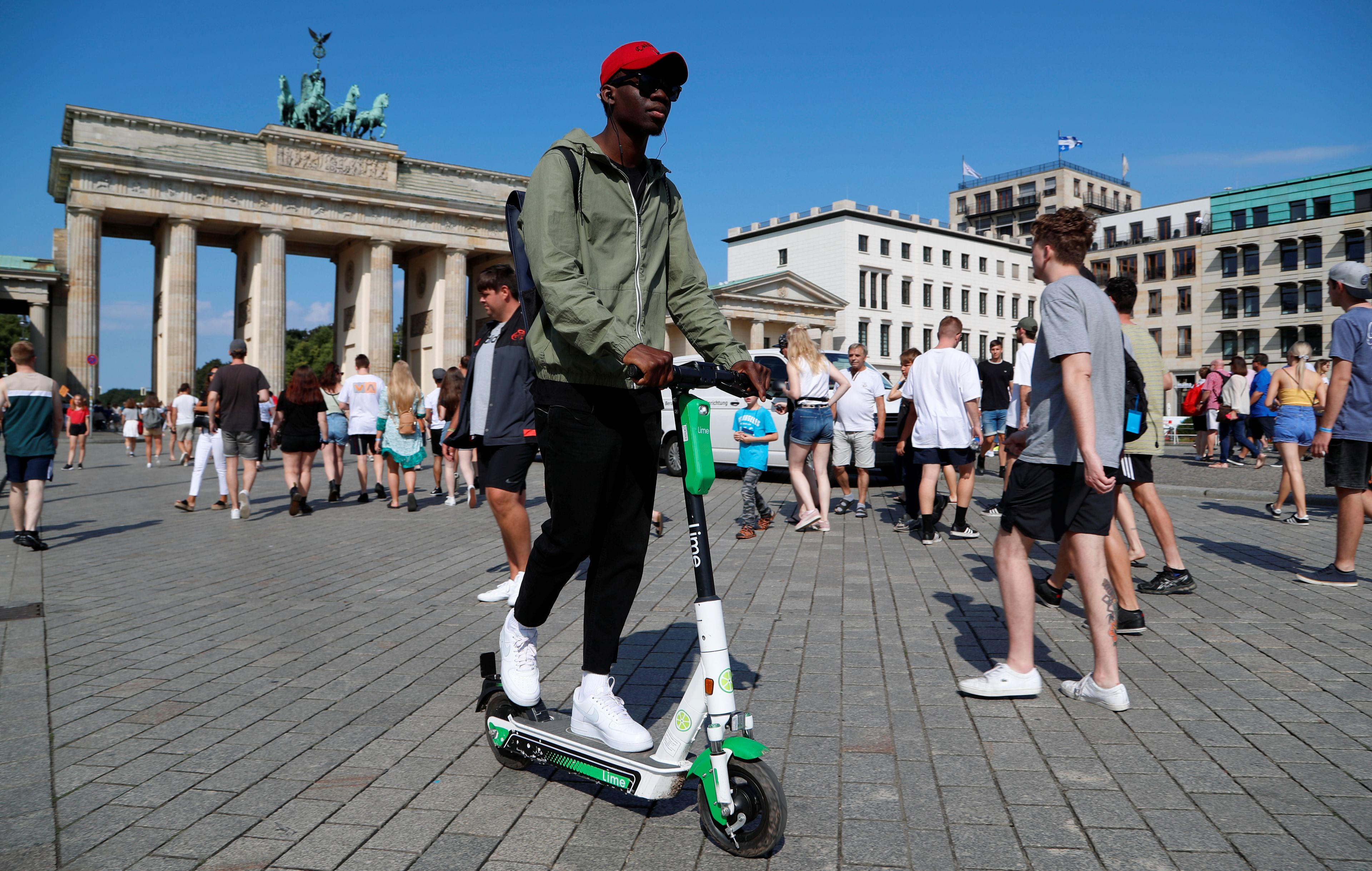 Un hombre conduce un patinete eléctrico compartido enfrente de la Puerta de Brandemburgo, en Berlín, Alemania.