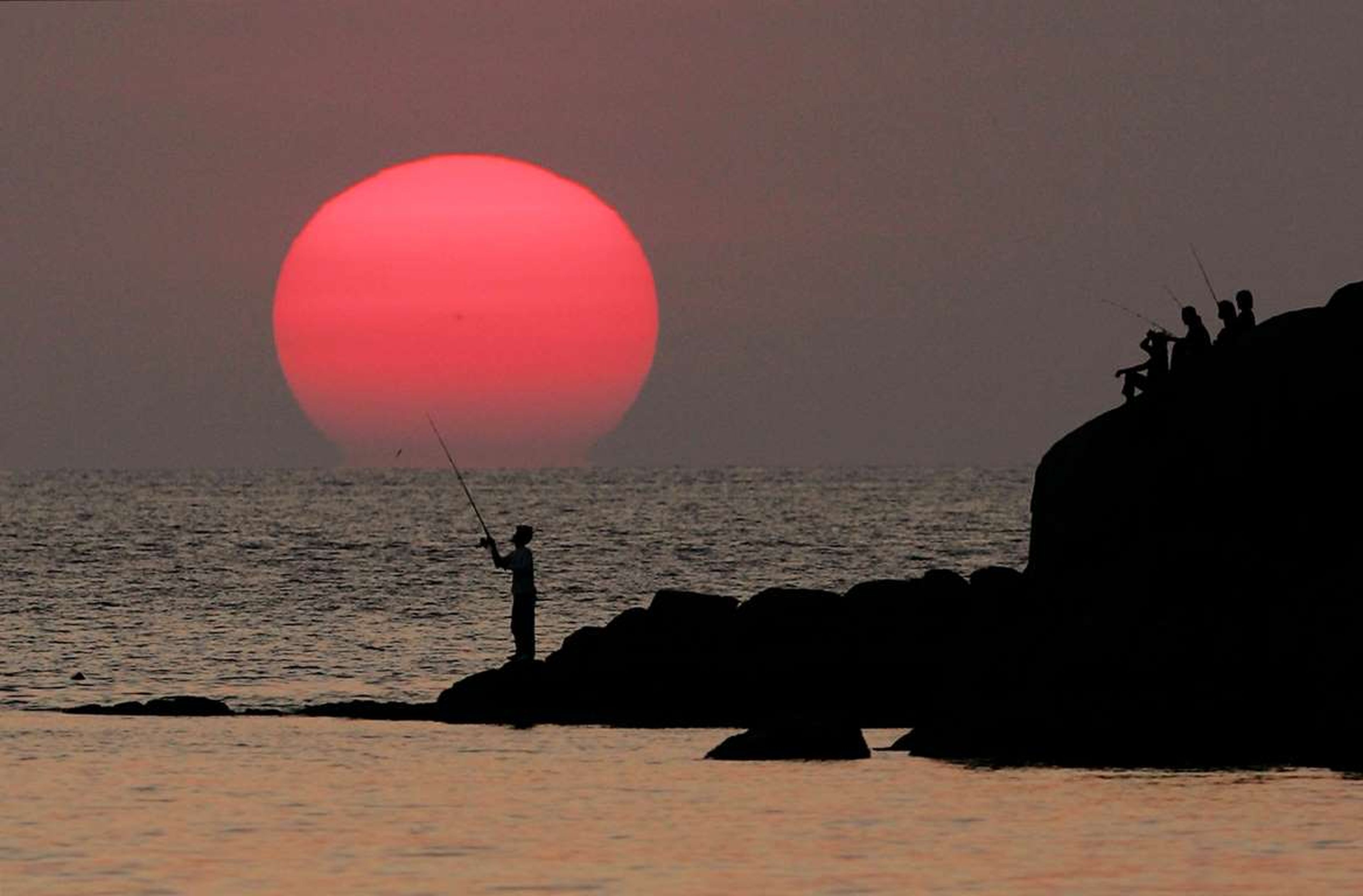 Un pescador tailandés pesca durante la puesta de sol, cerca de la playa Patong, en la isla de Phuket.