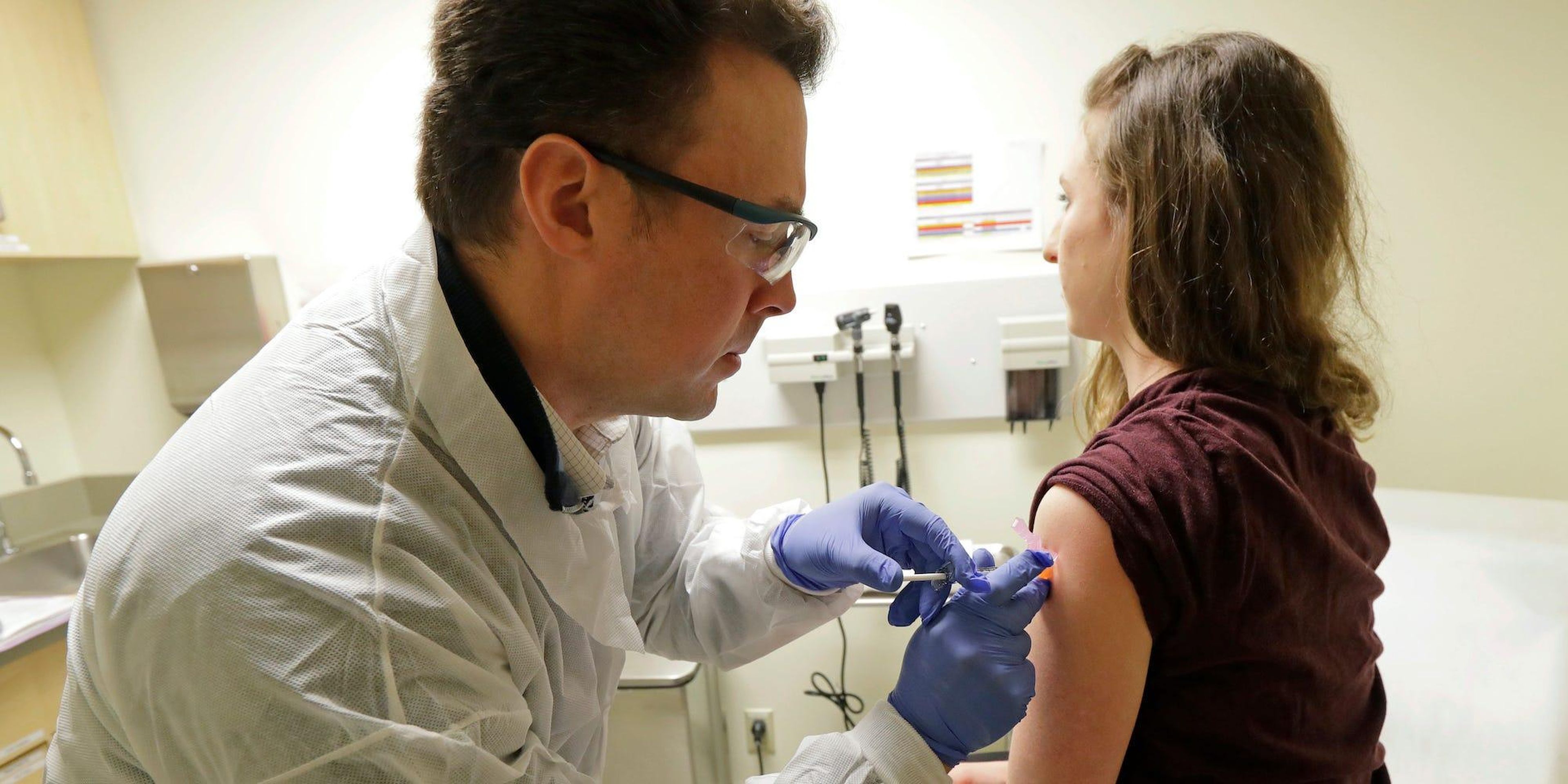 El farmacéutico Michael Witte inyecta a Rebecca Sirull en la primera fase del estudio clínico sobre una posible vacuna para covid-19.