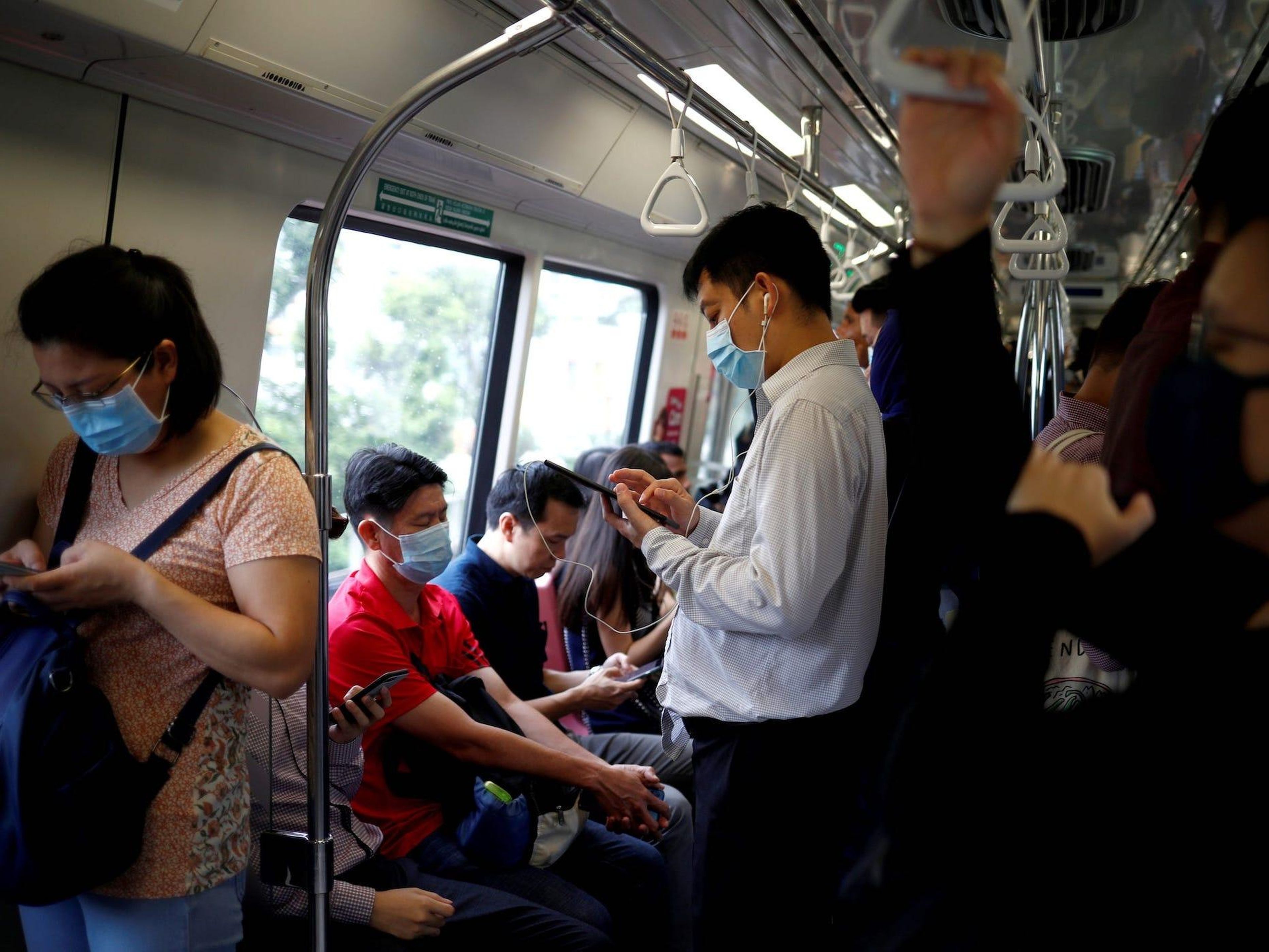Commuters wearing masks in precaution of the coronavirus outbreak are pictured in a train during their morning commute in Singapore February 18, 2020.