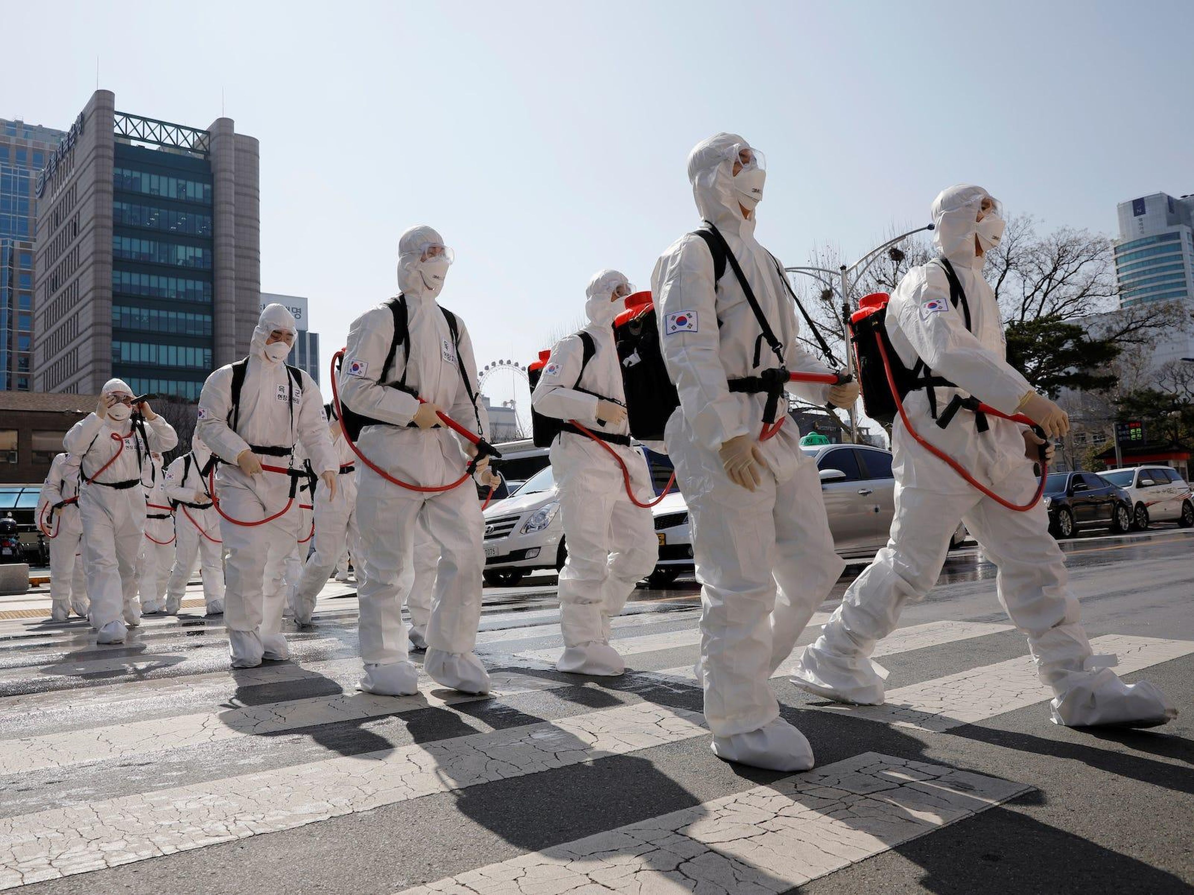 South Korean soldiers wearing protective gear walk on a street in front of Daegu's city hall after the rapid rise in confirmed cases of the coronavirus on March 2, 2020.