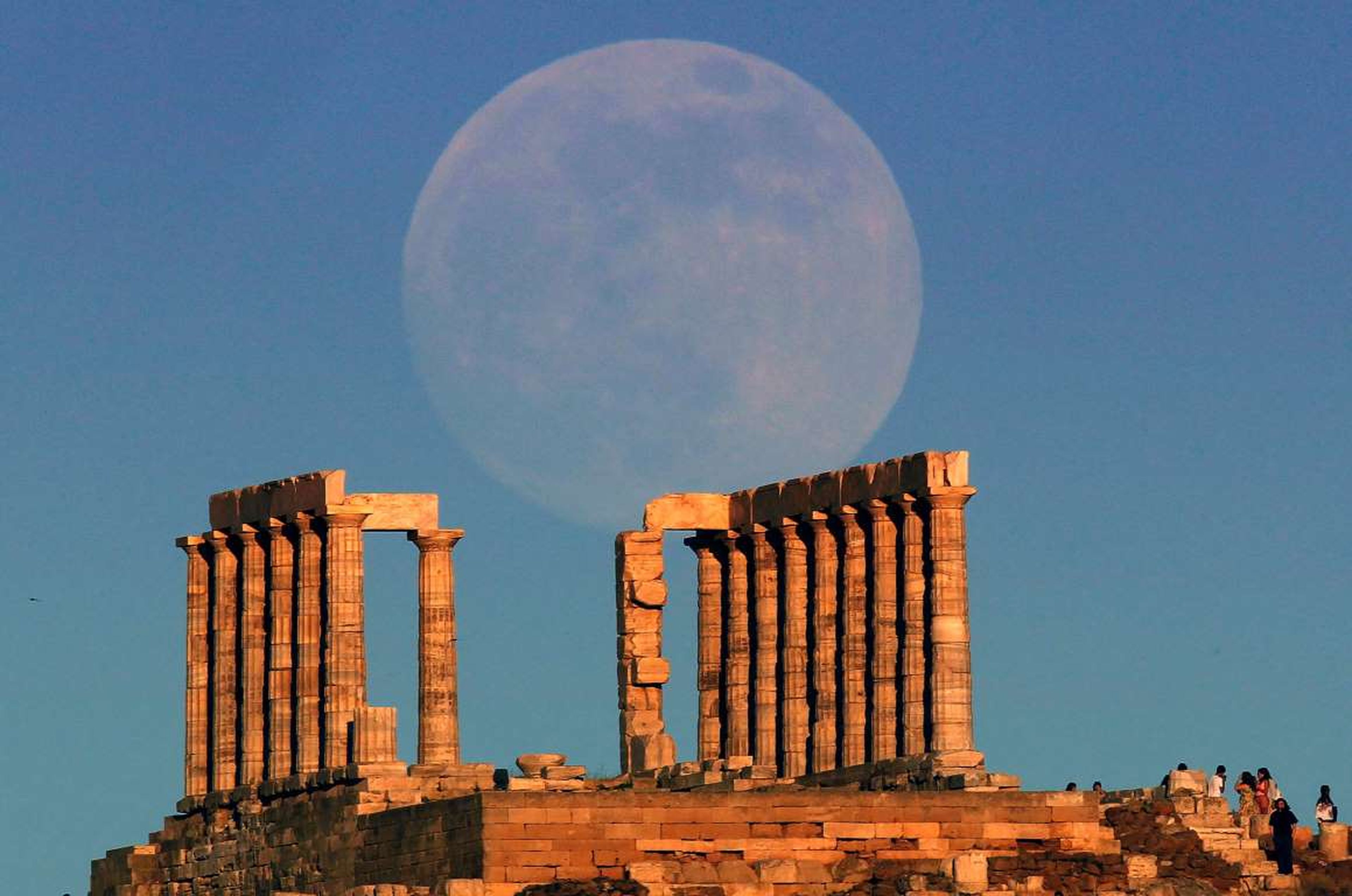 La súper luna se eleva sobre el templo de Poseidón, el dios griego de los mares, en Cabo Sunion, Grecia.
