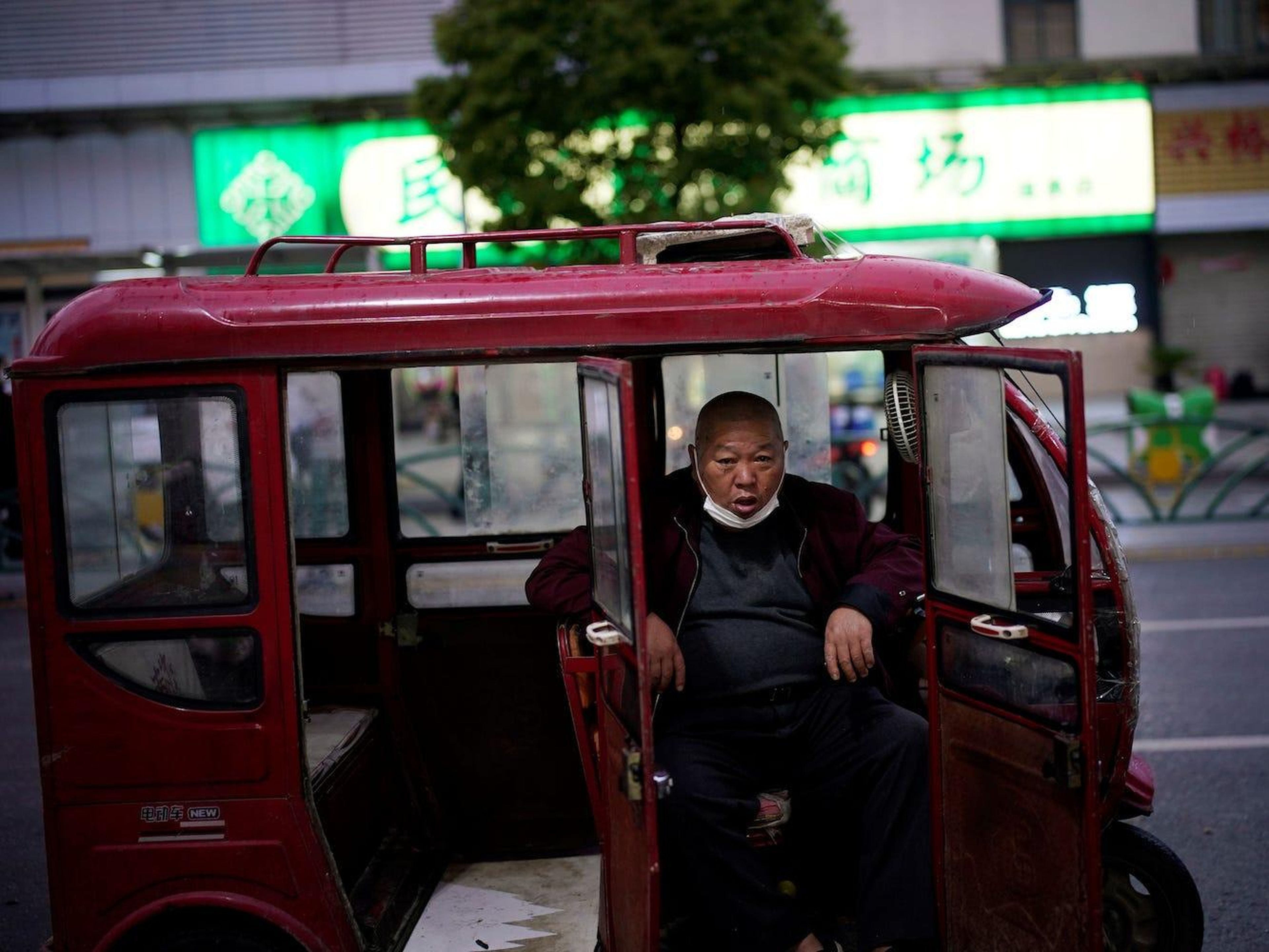 Un hombre con una mascarilla se sienta en su vehículo mientras espera clientes en Xianning, el 25 de marzo de 2020.