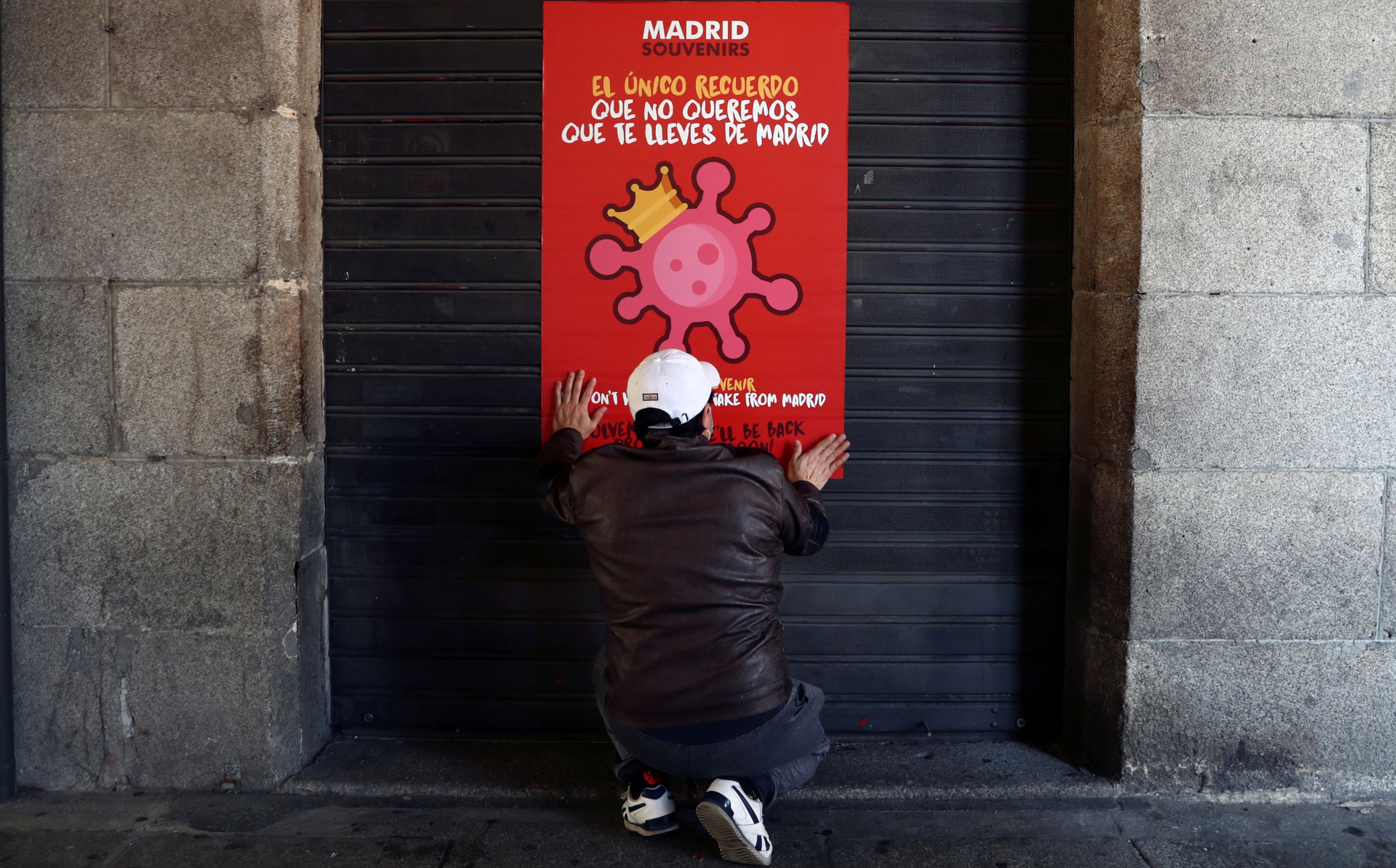 Un trabajador coloca un letrero explicando el cierre de su negocio por el estado de alarma por coronavirus en Madrid