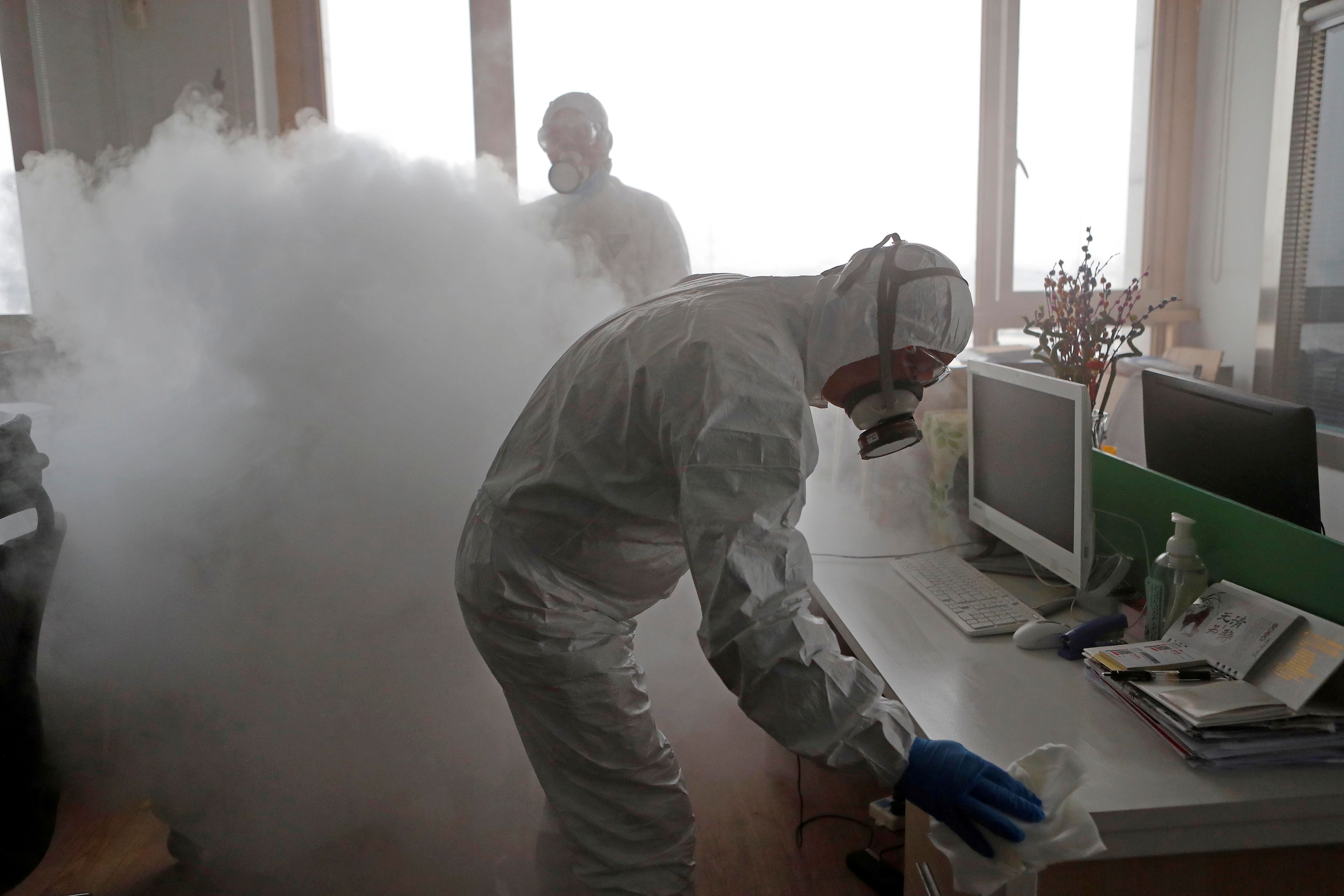 Trabajadores desinfectando un puesto de trabajo en una oficina.