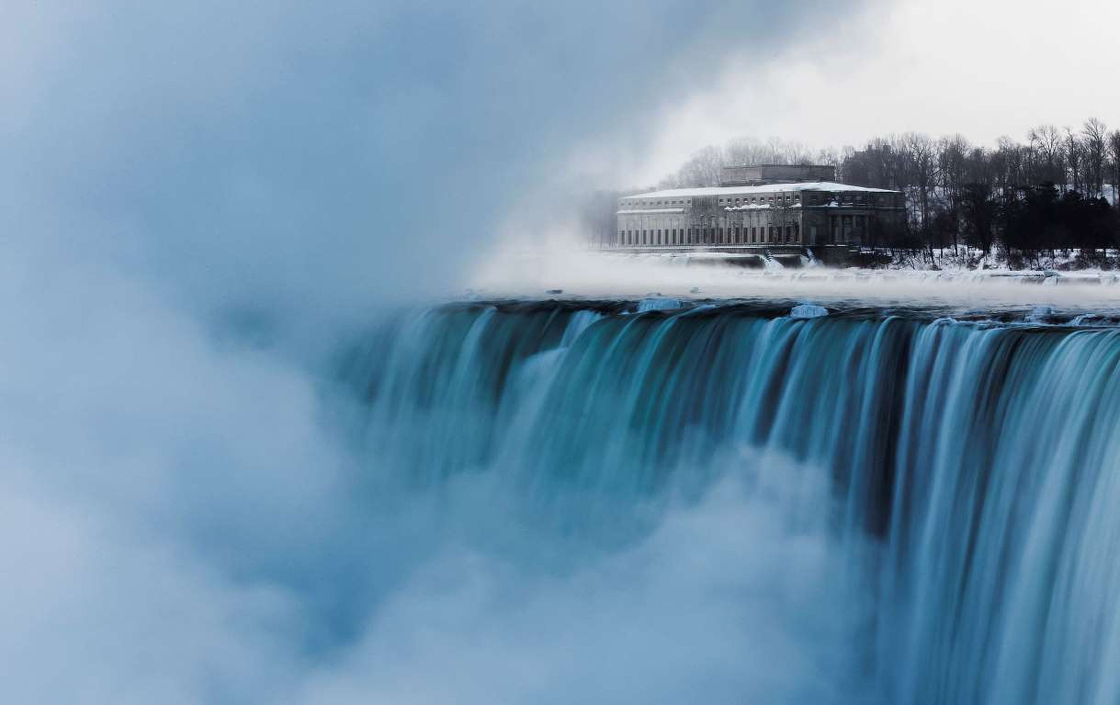 El viejo edificio de una hidroeléctrica se ve detrás de las Cataratas del Niagara, con temperaturas bajo cero, en Ontario.