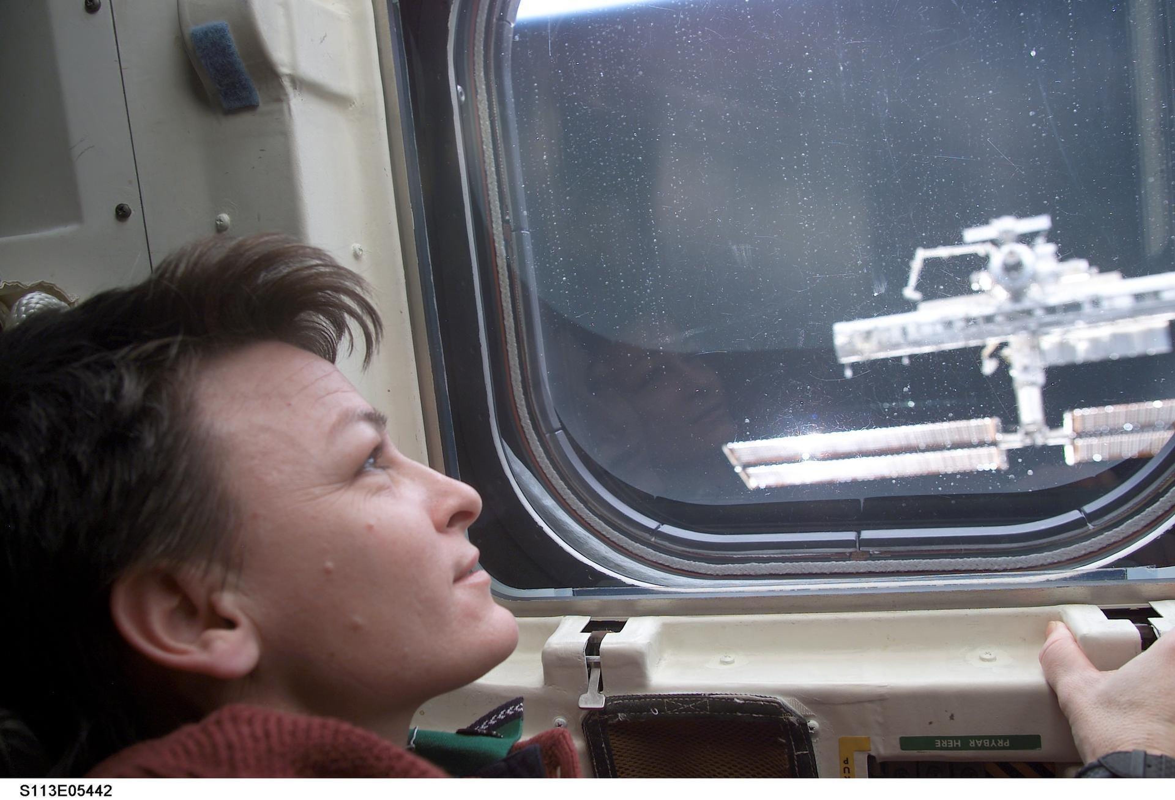 La astronauta Peggy Whitson mirando hacia la EEI a través de una ventana del transbordador espacial Endeavour.