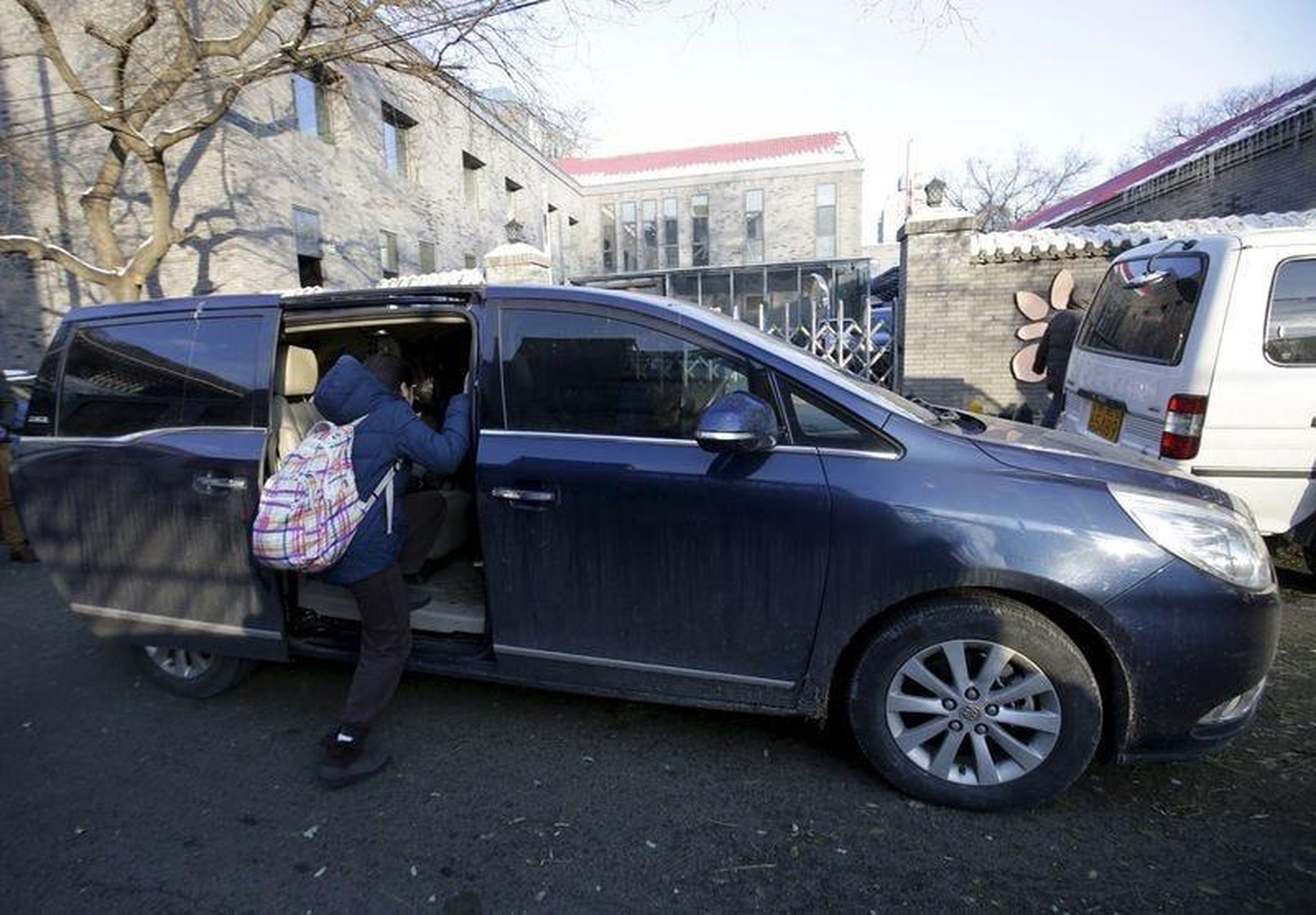 Una estudiante de primaria se sube a una minivan mientras su madre la recoge del colegio, en Pekín.