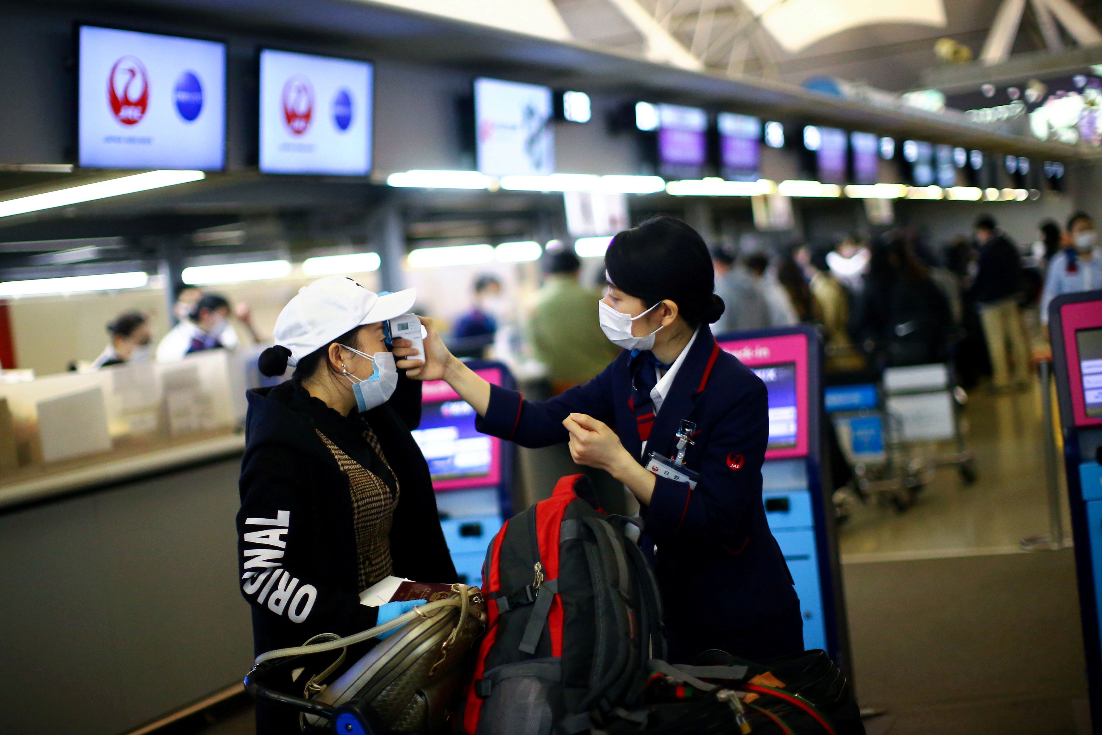 Una empleada de Japan Airlines mide la temperatura de una pasajera en plena pandemia del COVID-19 en el Aeropuerto Internacional de Kansai, en Osaka, Japón.