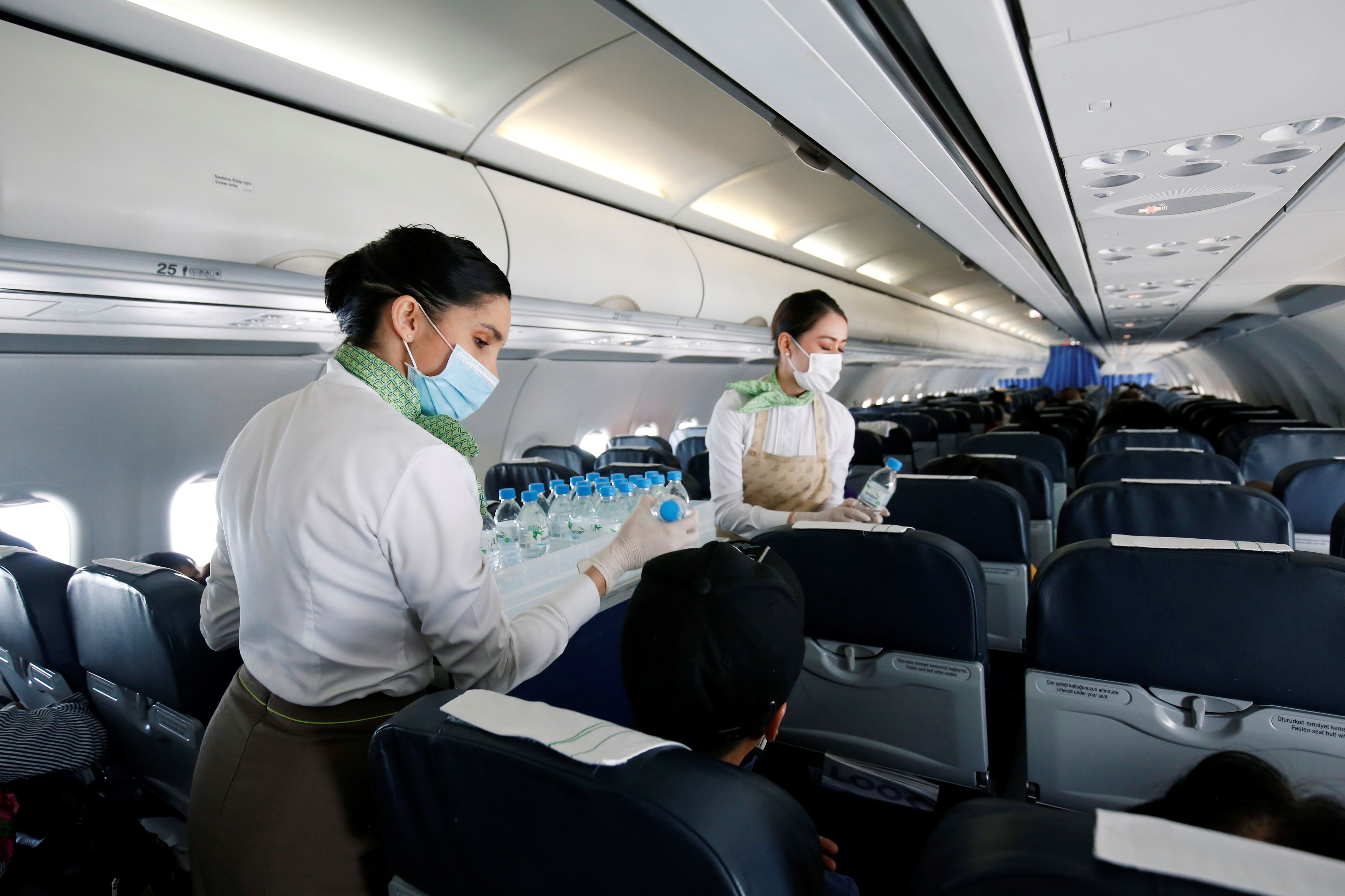Tripulantes de cabina de pasajeros sirven agua en un vuelo de Bamboo Airway en Vietnam.