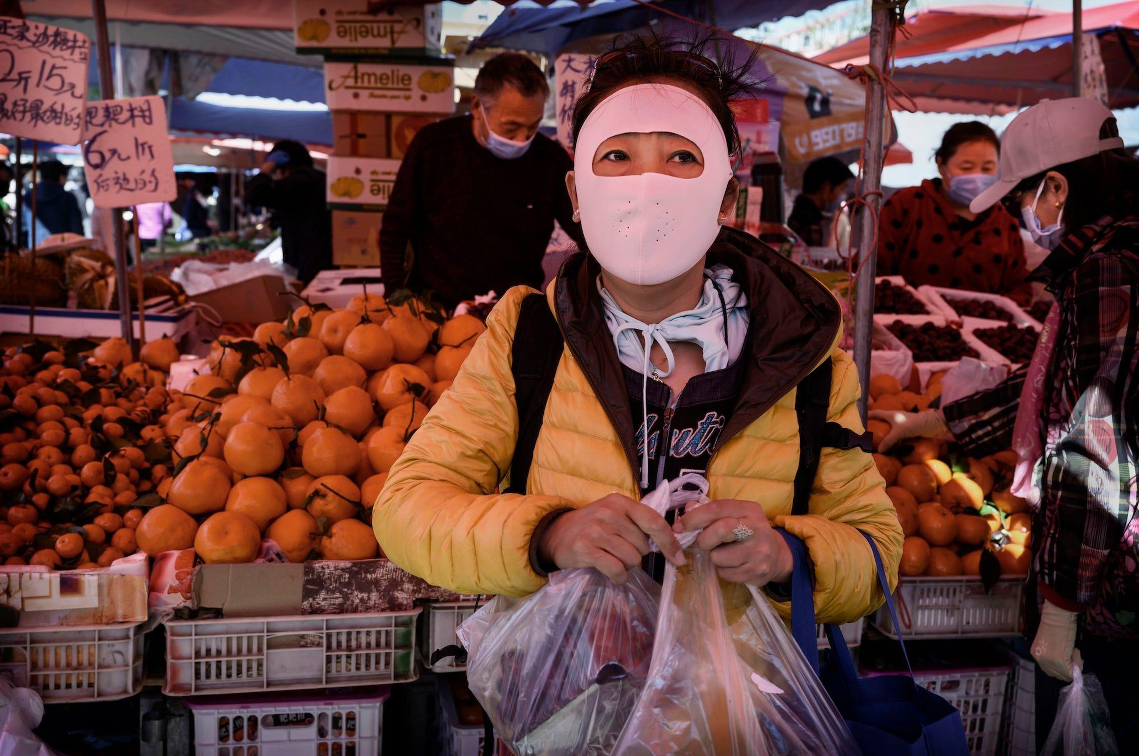 Una mujer china utiliza una máscara protectora que cubre todo su rostro mientras compra en un mercado al aire libre en Pekín, China, el 3 de abril de 2020.
