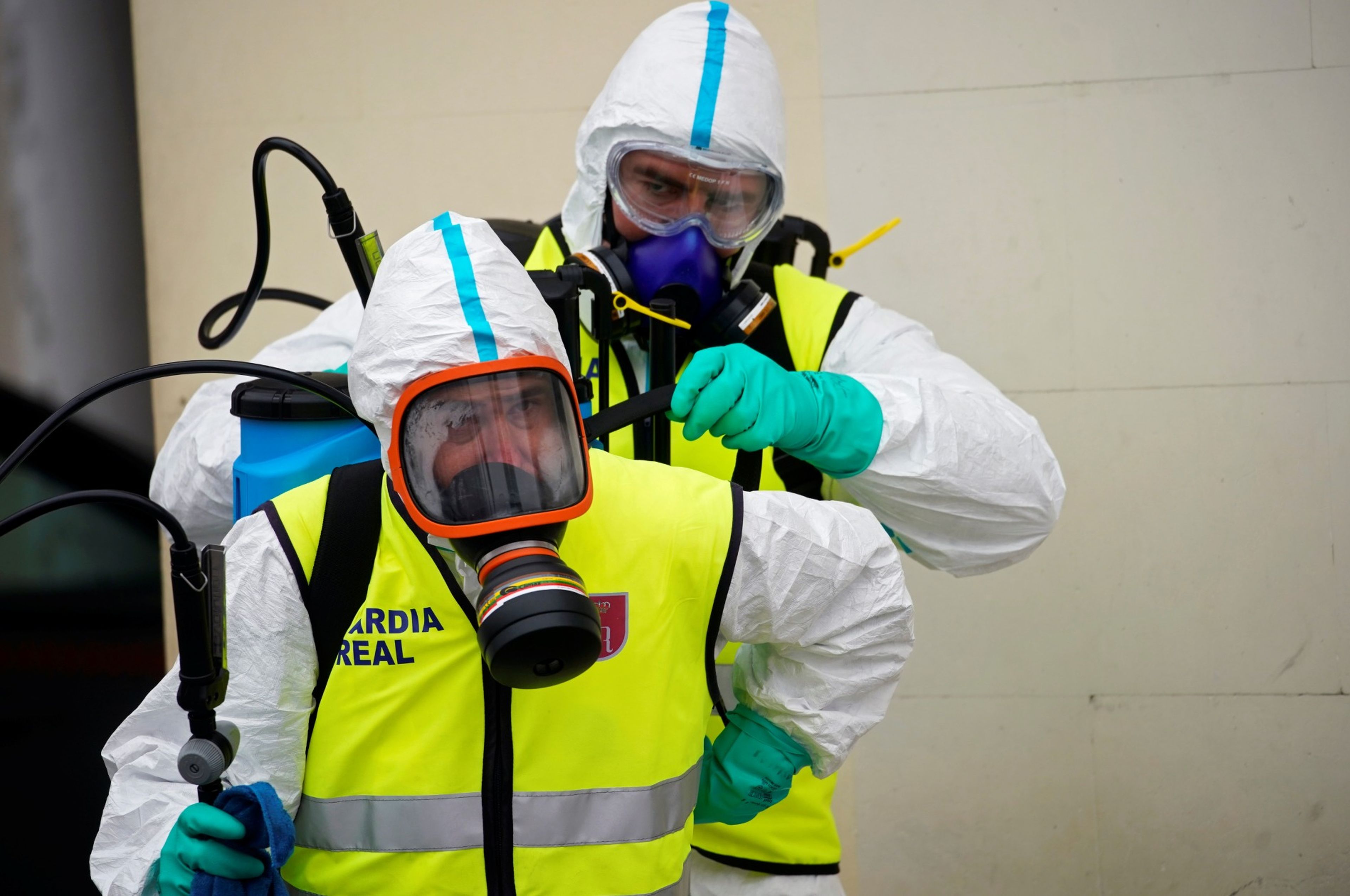Dos miembros de la Guardia Real se ponen el equipamiento para protegerse del coronavirus.