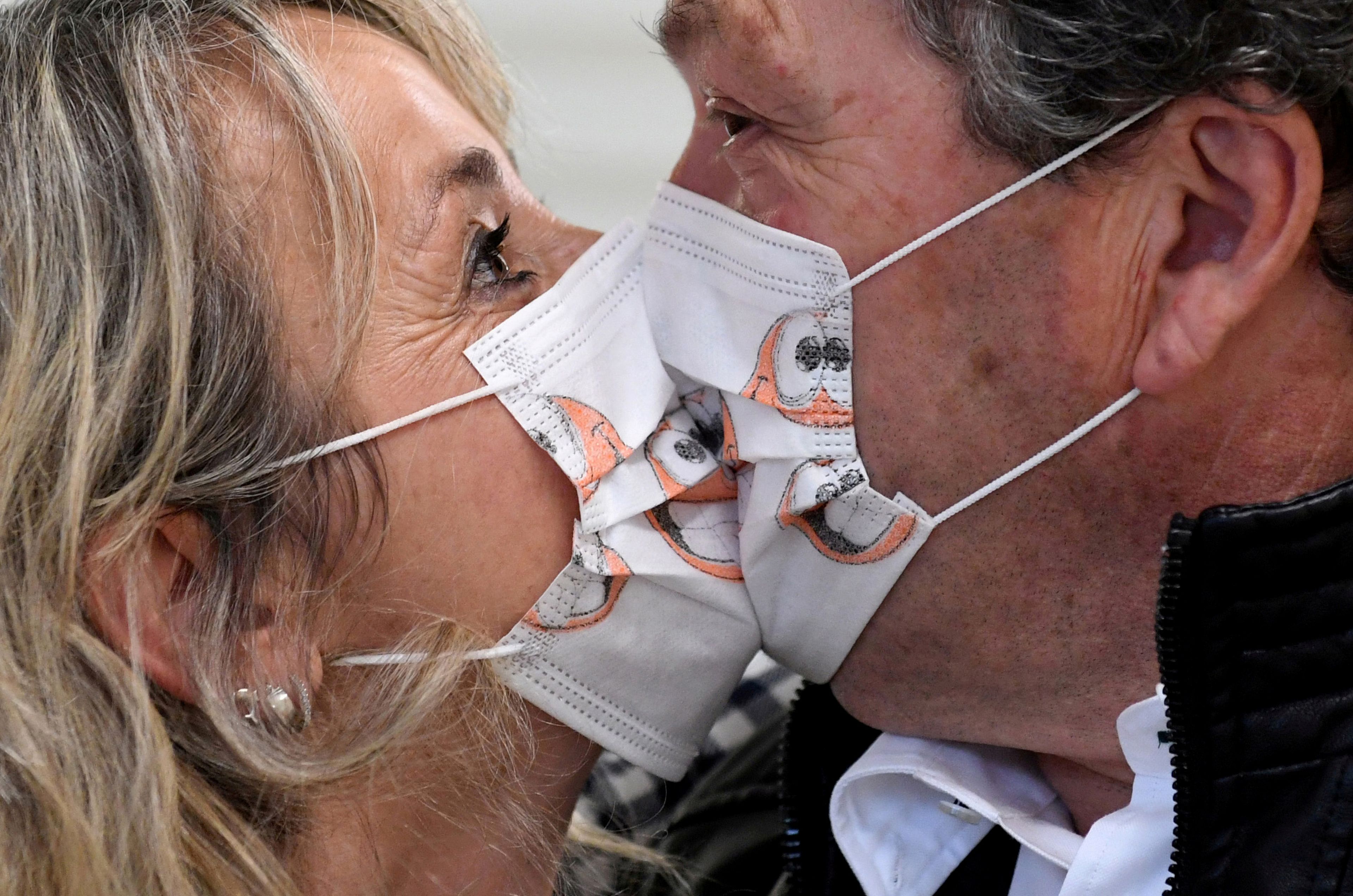 Dos personas con mascarillas besándose