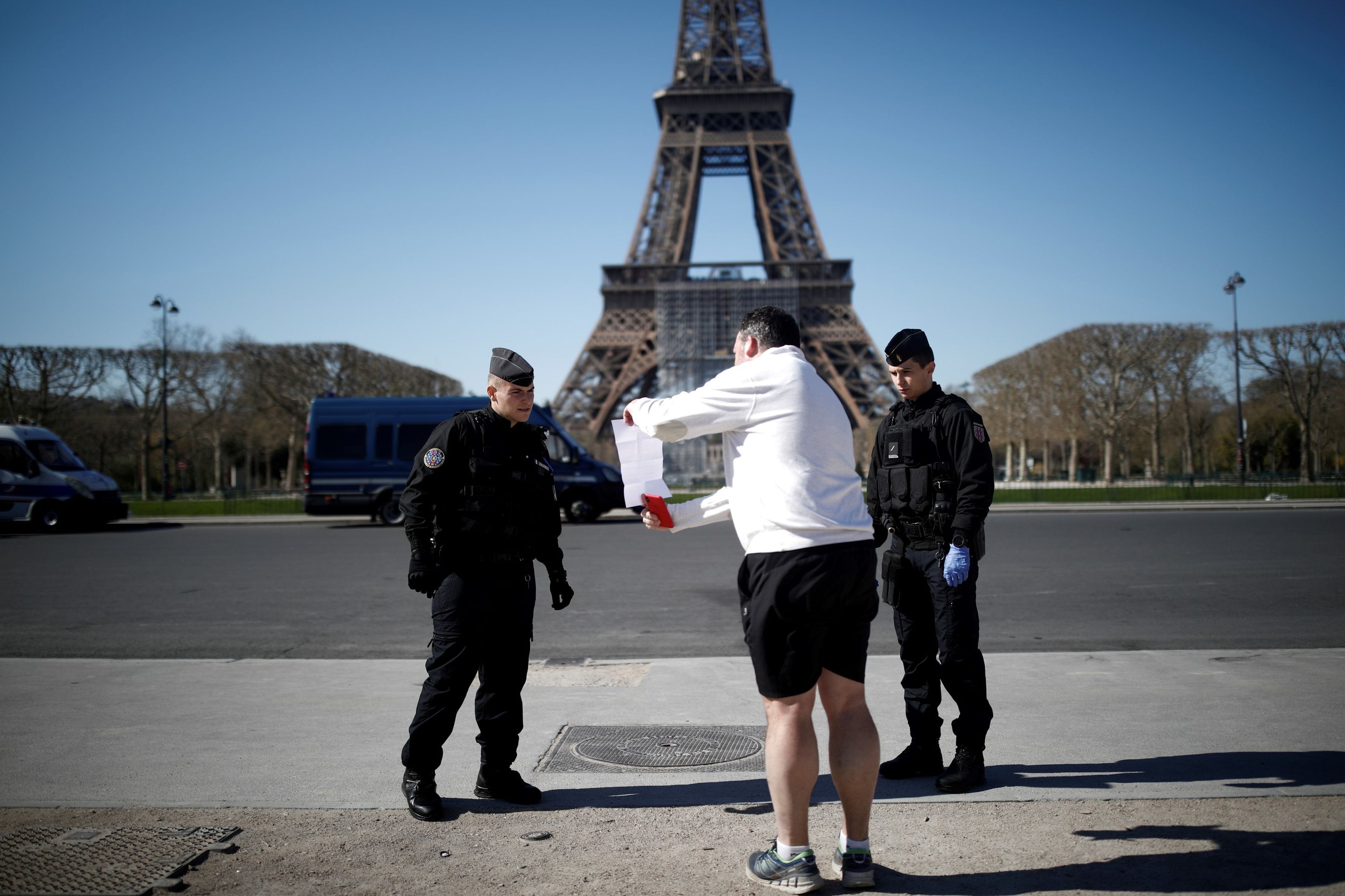Gendarmes franceses al pie de la Torre Eiffel comprueban el justificante de un ciudadano en la calle en pleno confinamiento