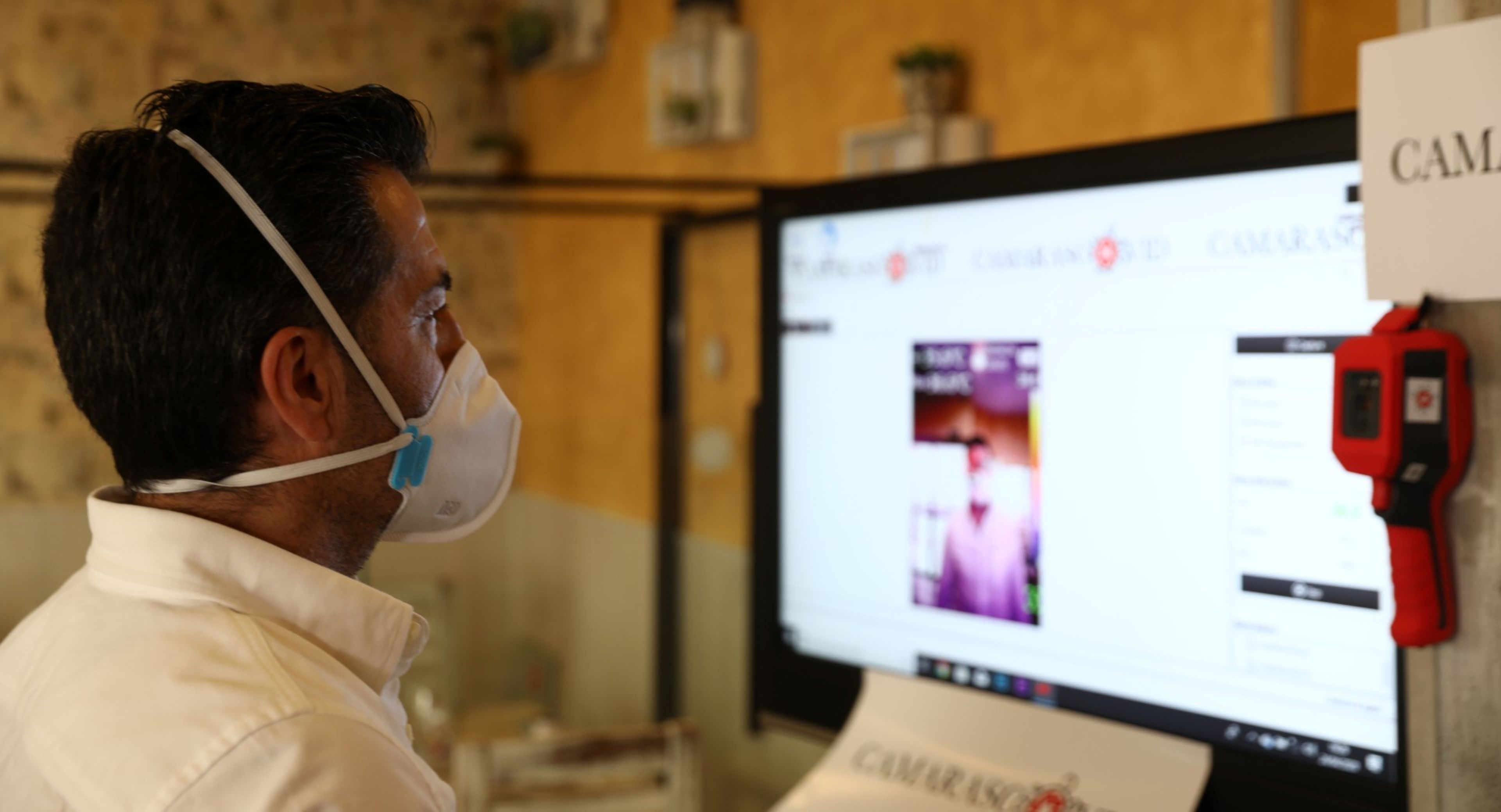 Un hombre delante de un ordenador con mascarilla por el coronavirus.