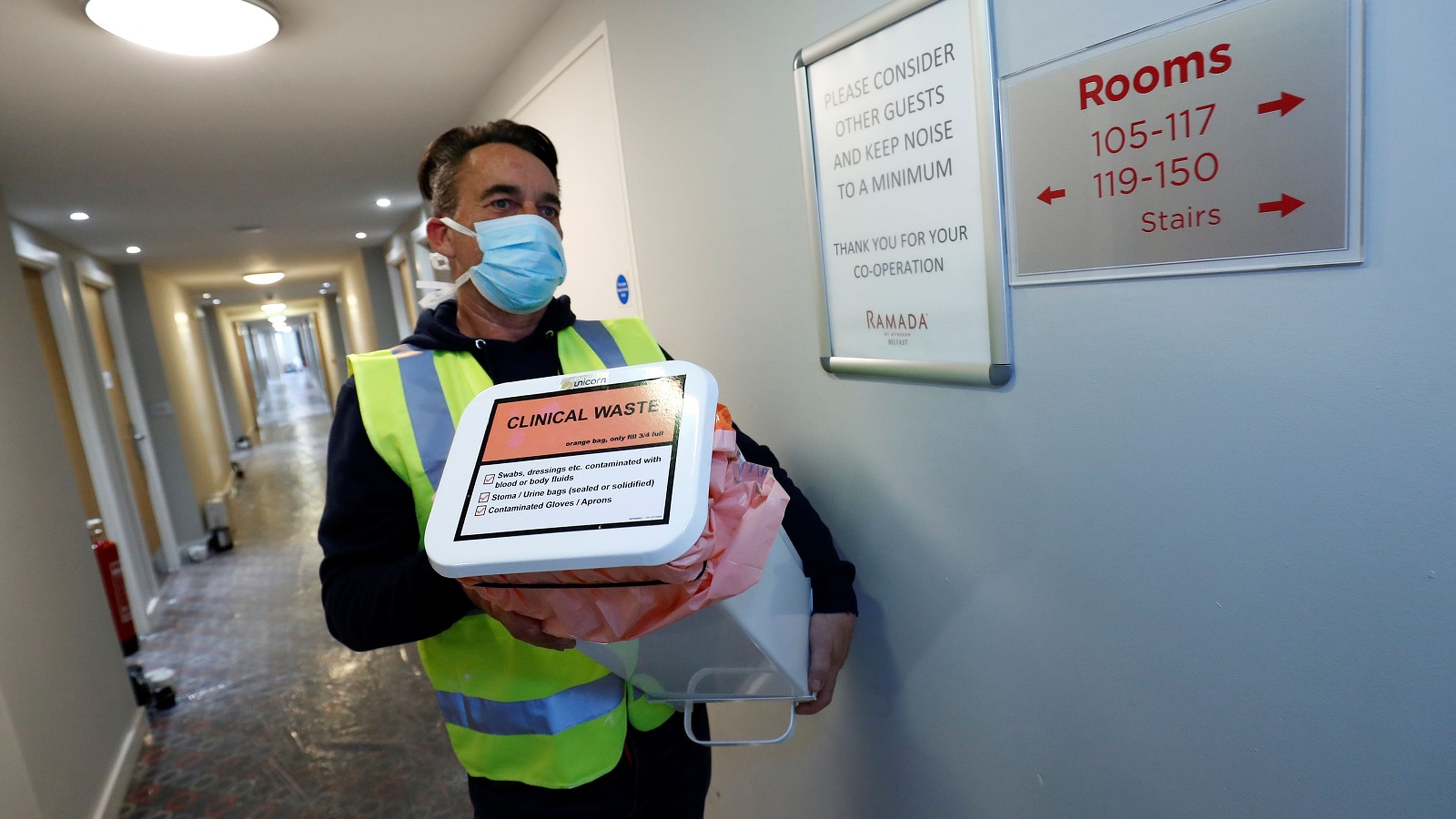 Un hombre con mascarilla lleva material sanitario en los pasillios de un hotel.