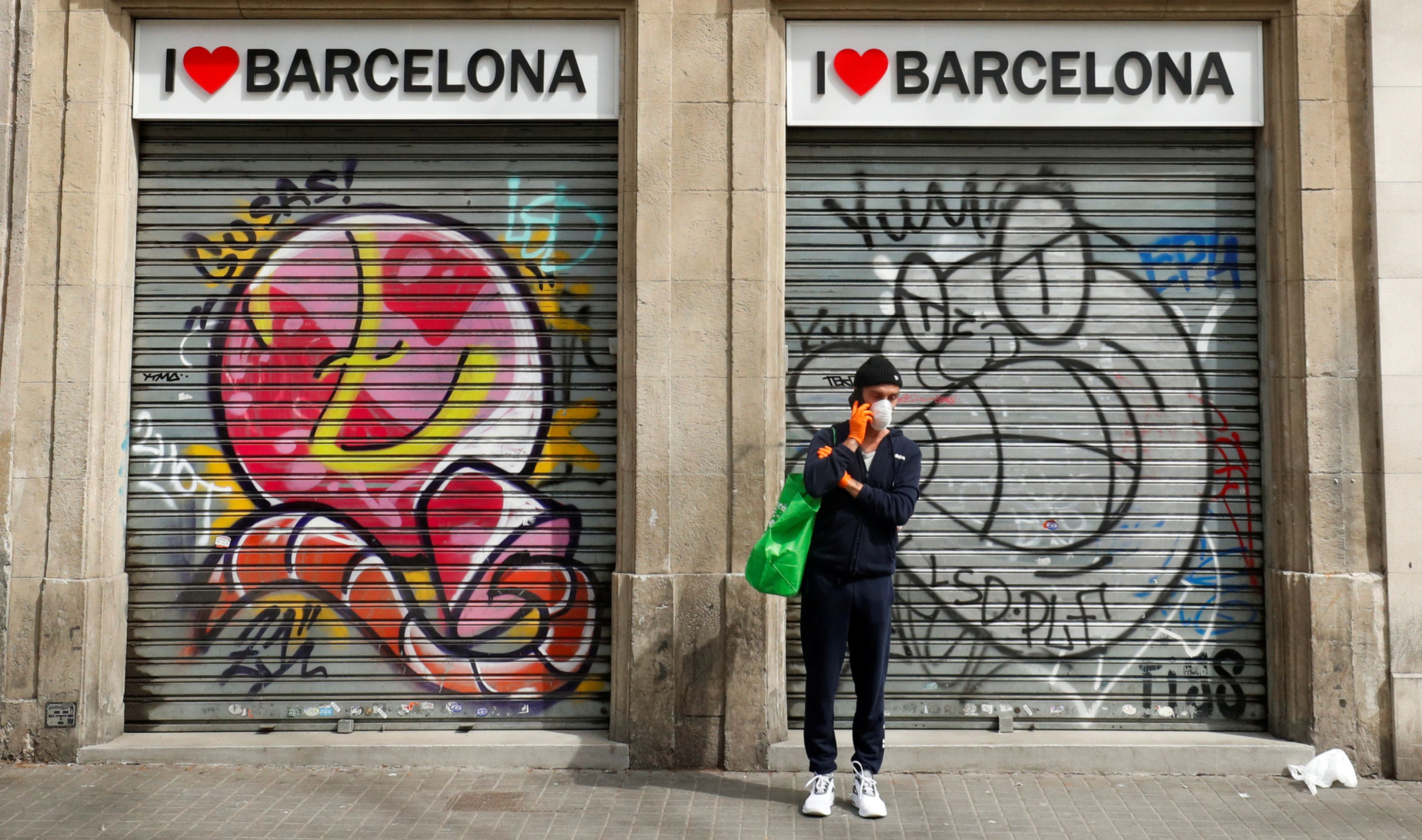 Un hombre con mascarilla, ante una tienda de souvenirs cerrada en Barcelona