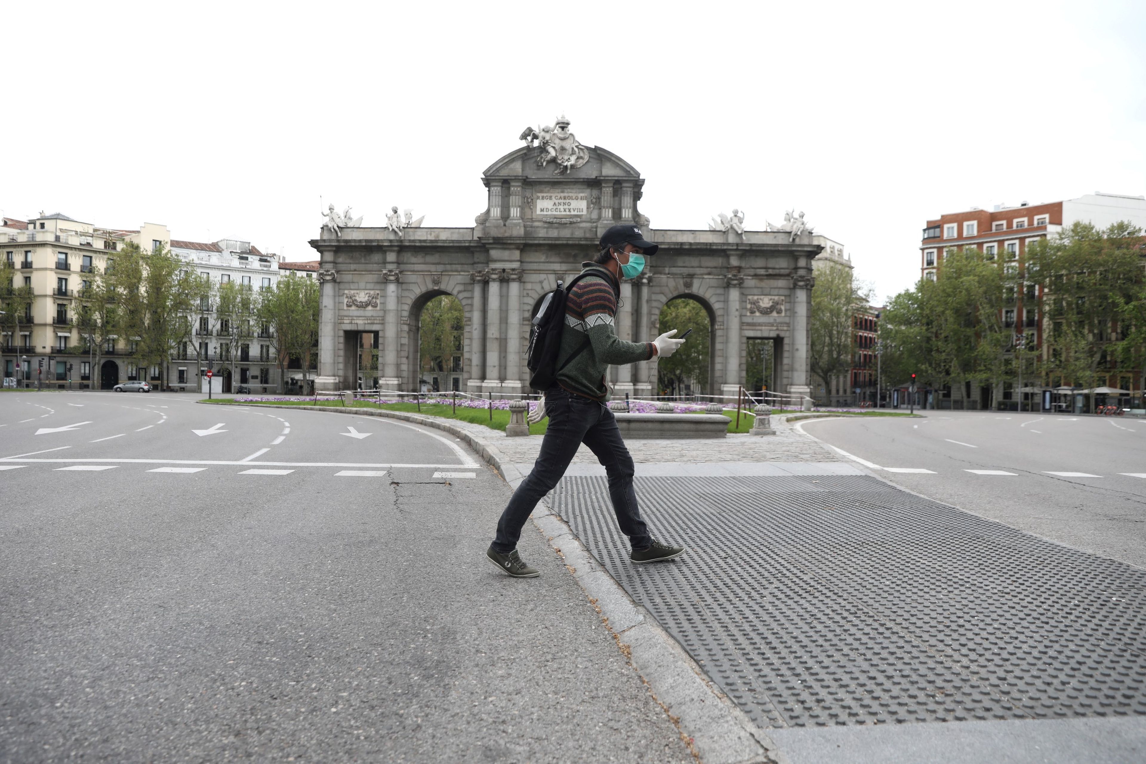 Un hombre pasea por delante de la Puerta de Alcalá en medio del confinamiento por el coronavirus
