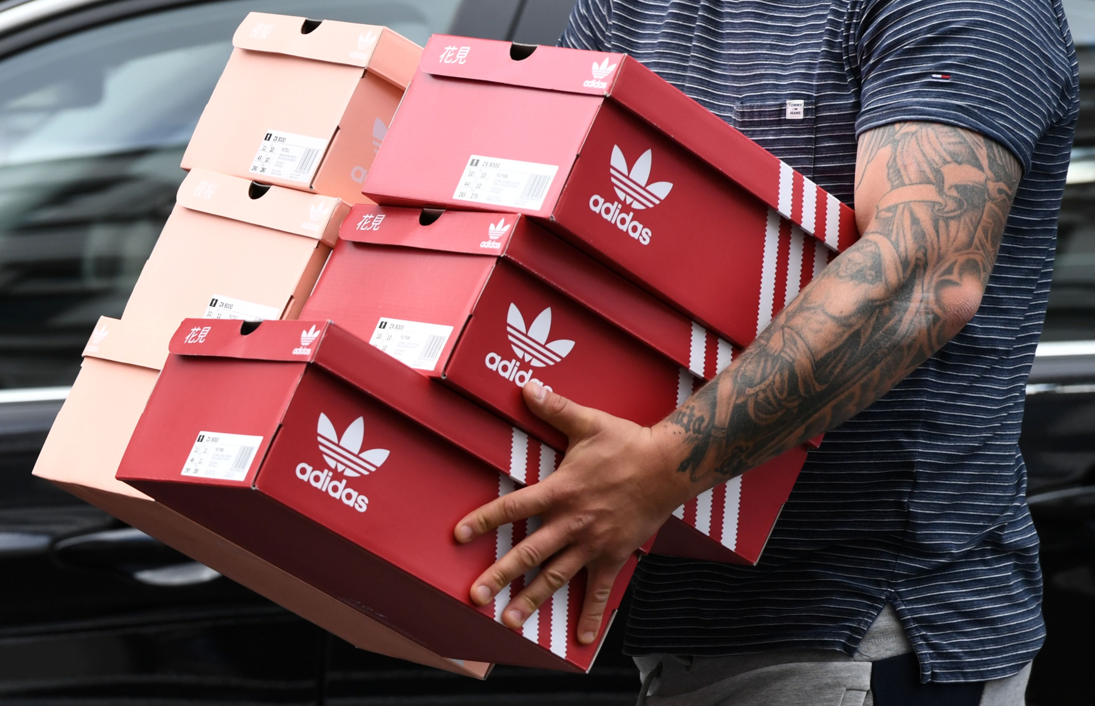 Un hombre con varias cajas de zapatillas de Adidas en Berlín