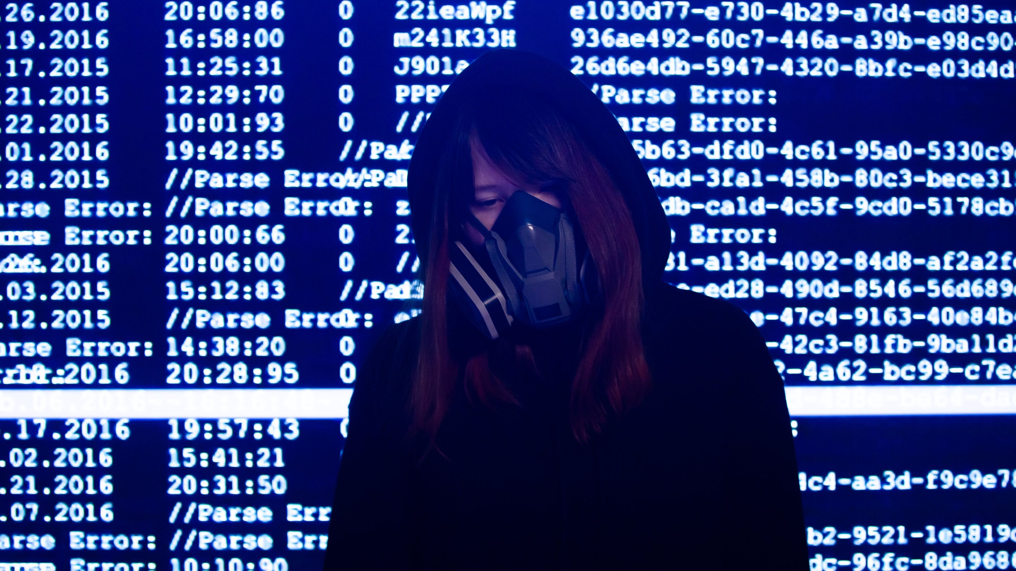 Una mujer con una máscara delante de una pantalla de datos