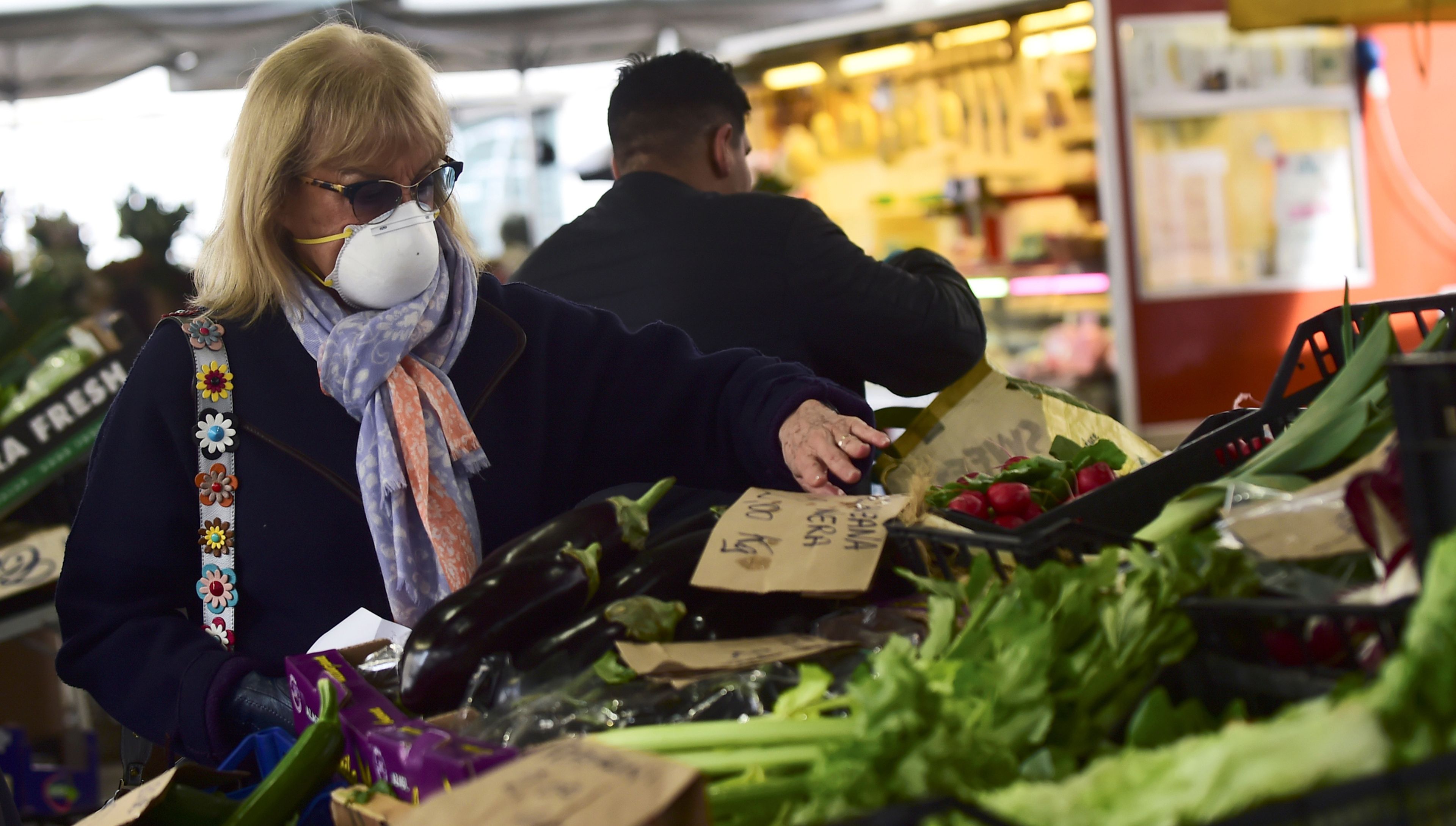 Una mujer con mascarilla compra verdura en un mercado de Turín (Italia)