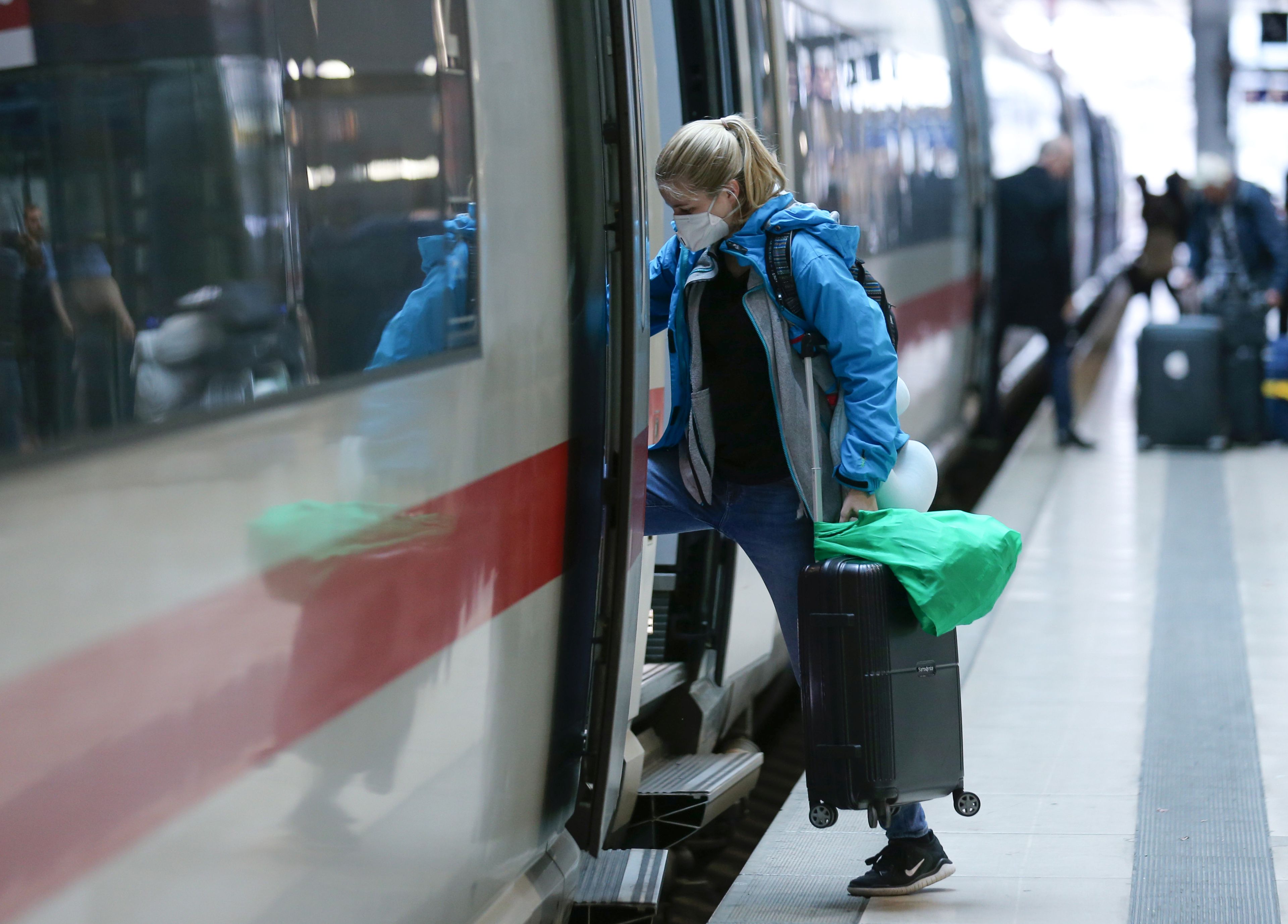 Una mujer sube a un tren en Alemania con mascarilla por el coronavirus.