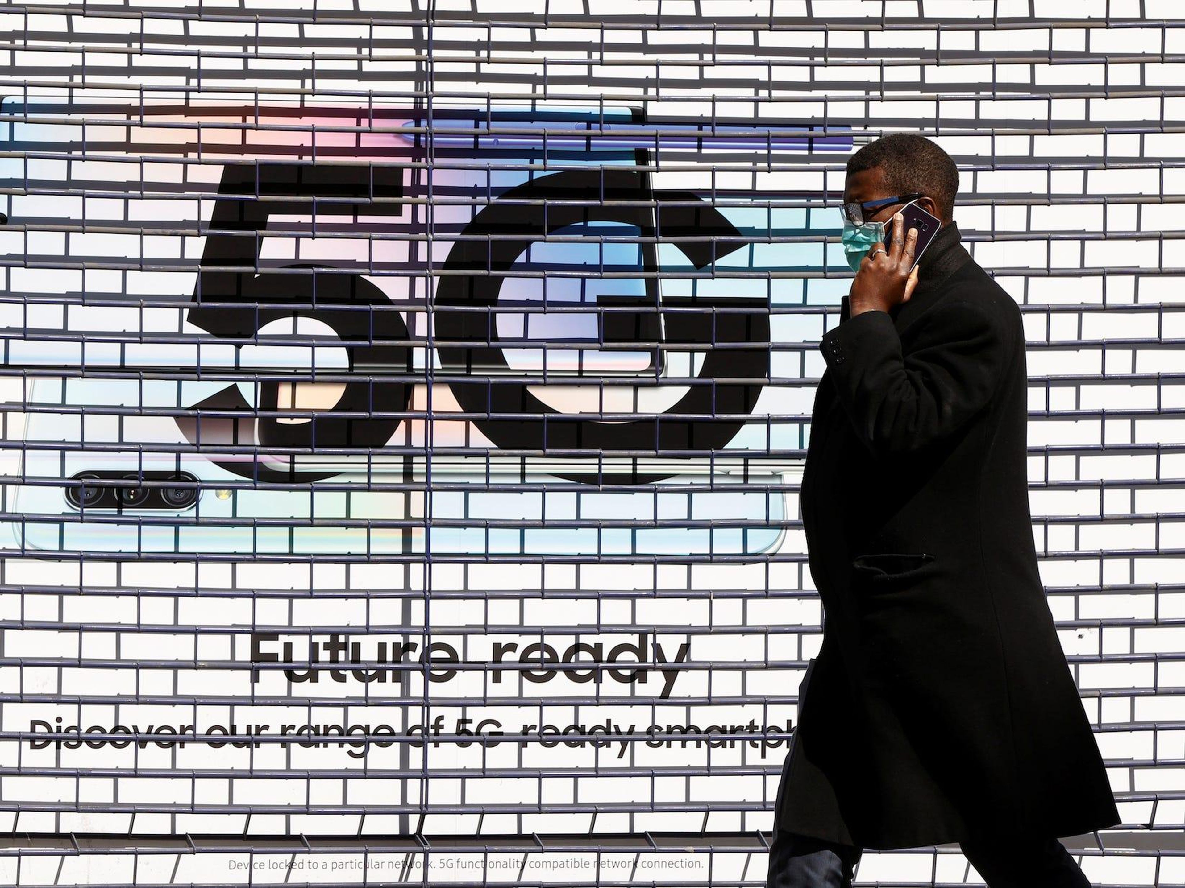 Un peatón pasa por delante de un anuncio que promociona la red de datos 5G en una tienda de teléfonos móviles en Londres en enero de 2020.