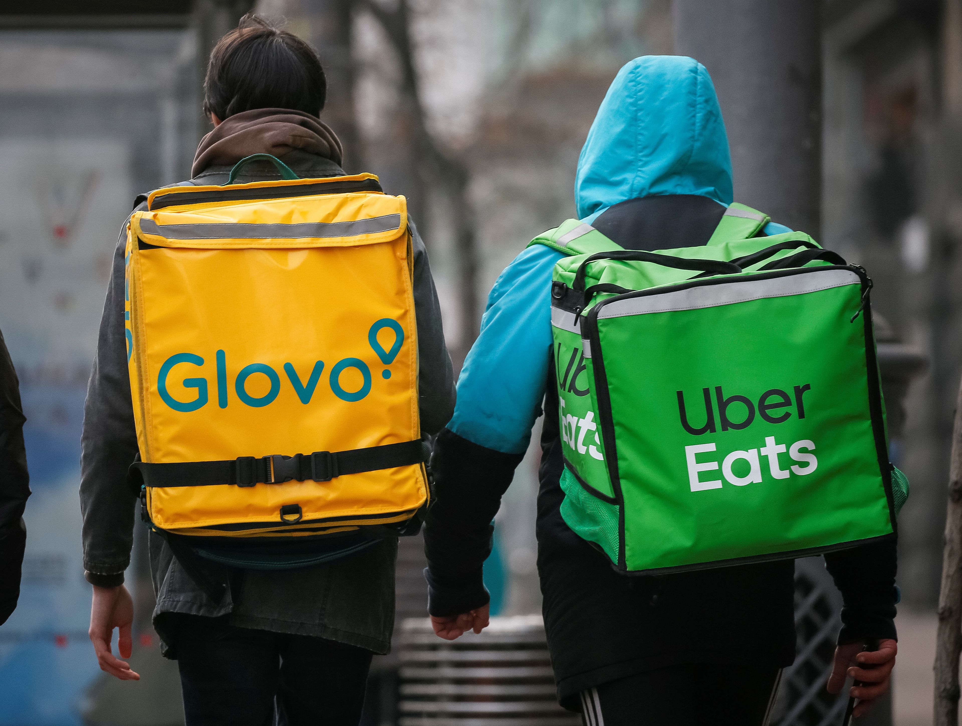 Un 'rider' de Glovo y otro de Uber Eats caminan por una calle principal de Kiev.