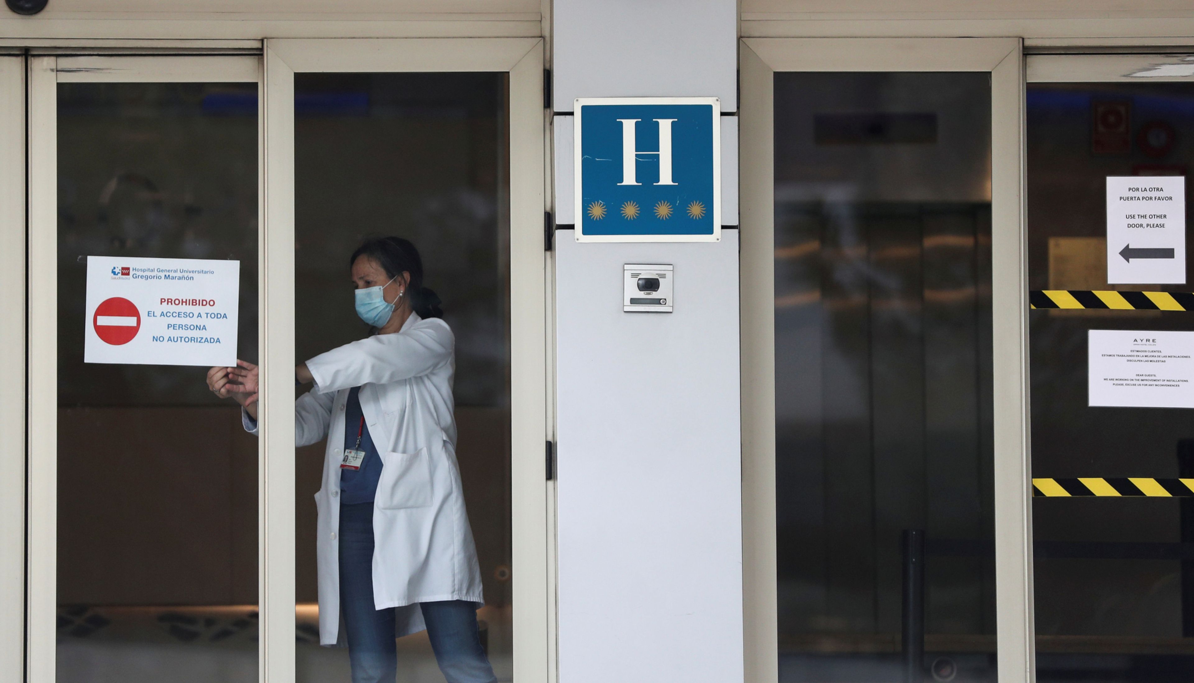 Una trabajadora sanitaria coloca un cartel en un hotel medicalizado en Madrid