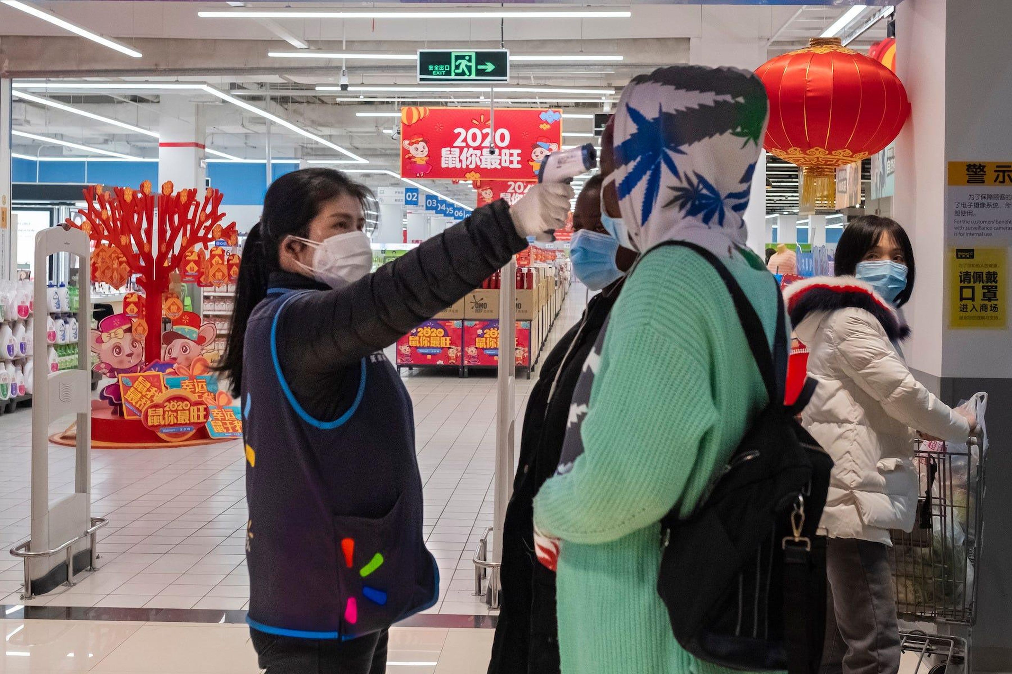 Una trabajadora toma la temperatura de un cliente en Walmart, en Wuhan, China.