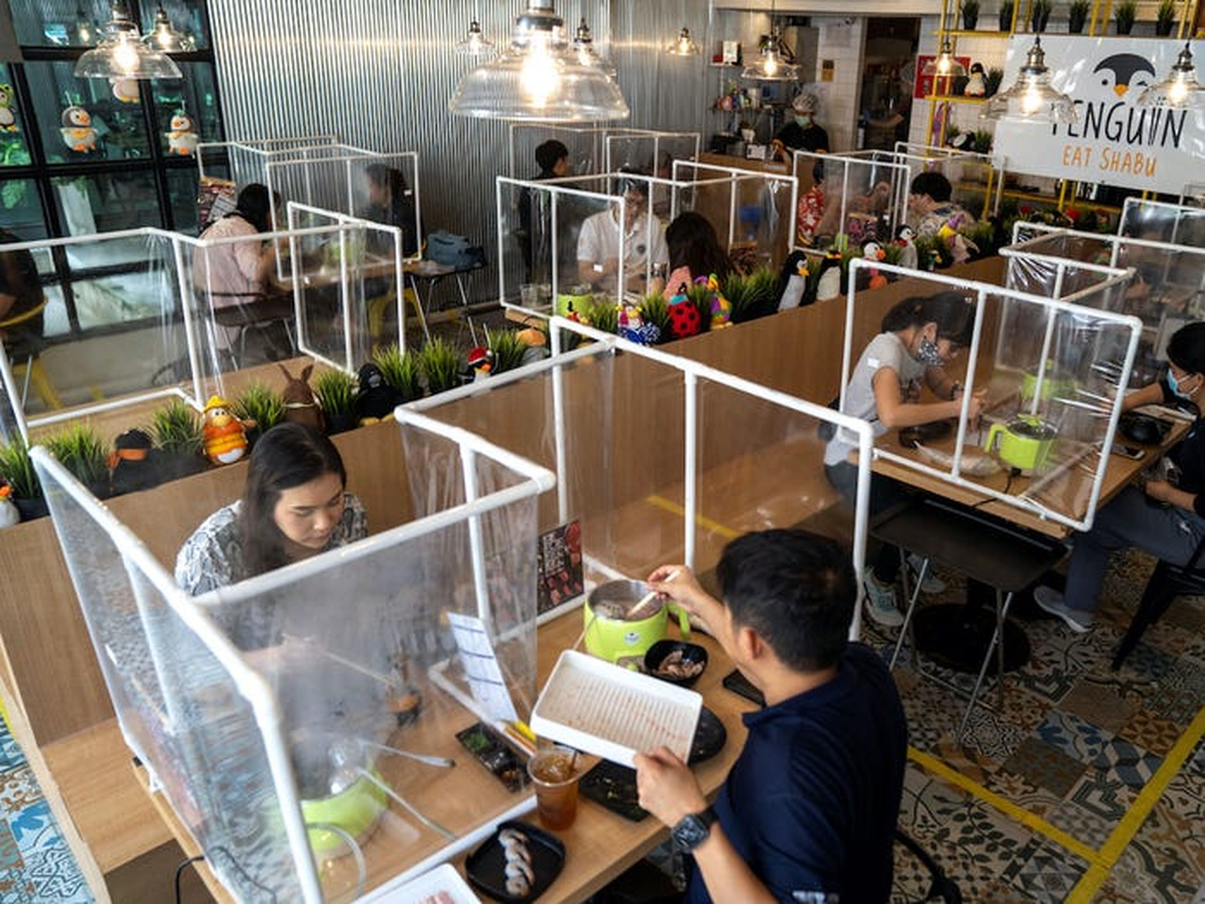 Una barrera de plástico permite a los clientes disfrutar de su estofado en un restaurante.