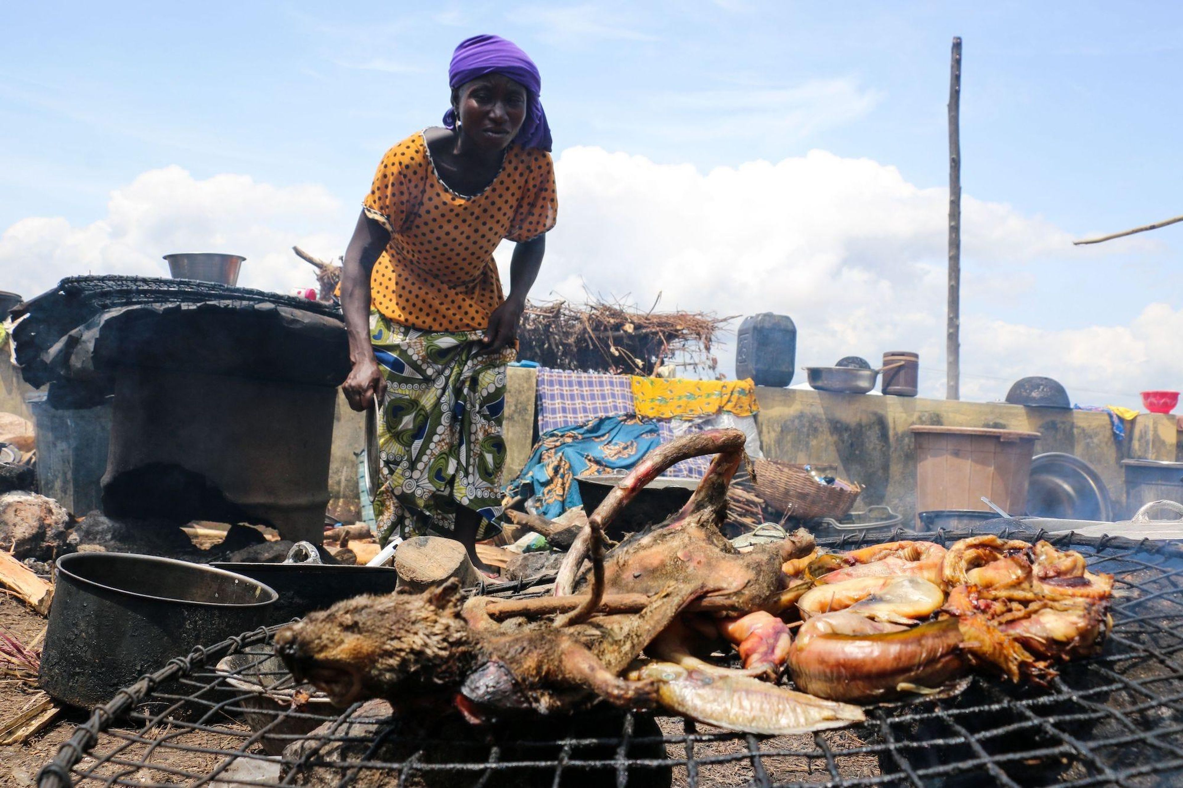 A woman displaced by the recent wave of floods in Konto Karfi, prepares to roast bushmeat at an outdoor facility of an Internally displaced people (IDPs) camp in Otokiti, Kogi State, on September 19, 2018