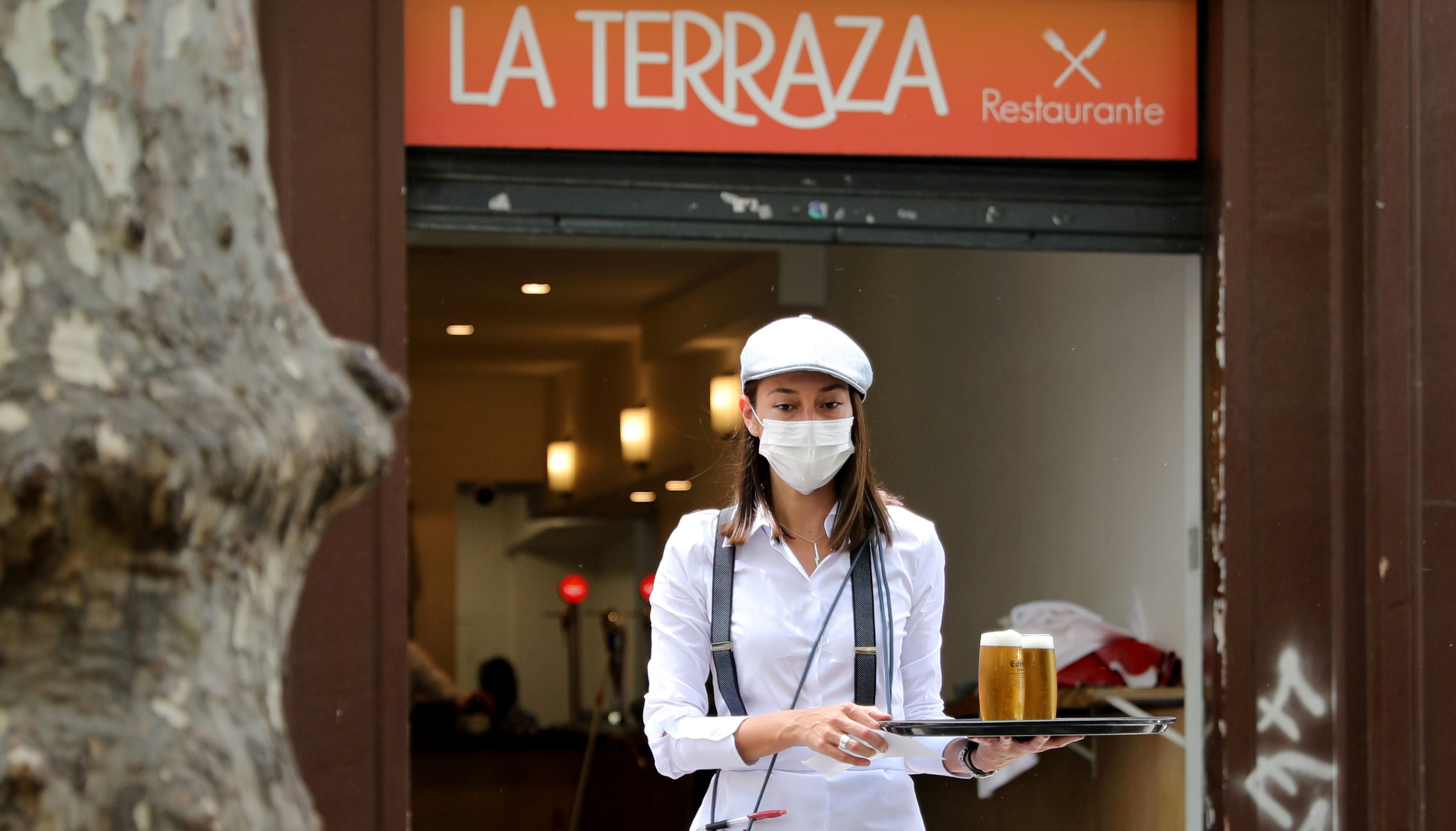 Una camarera con mascarilla sirve 2 cañas en una terraza de Barcelona tras la reapertura de la hostelería