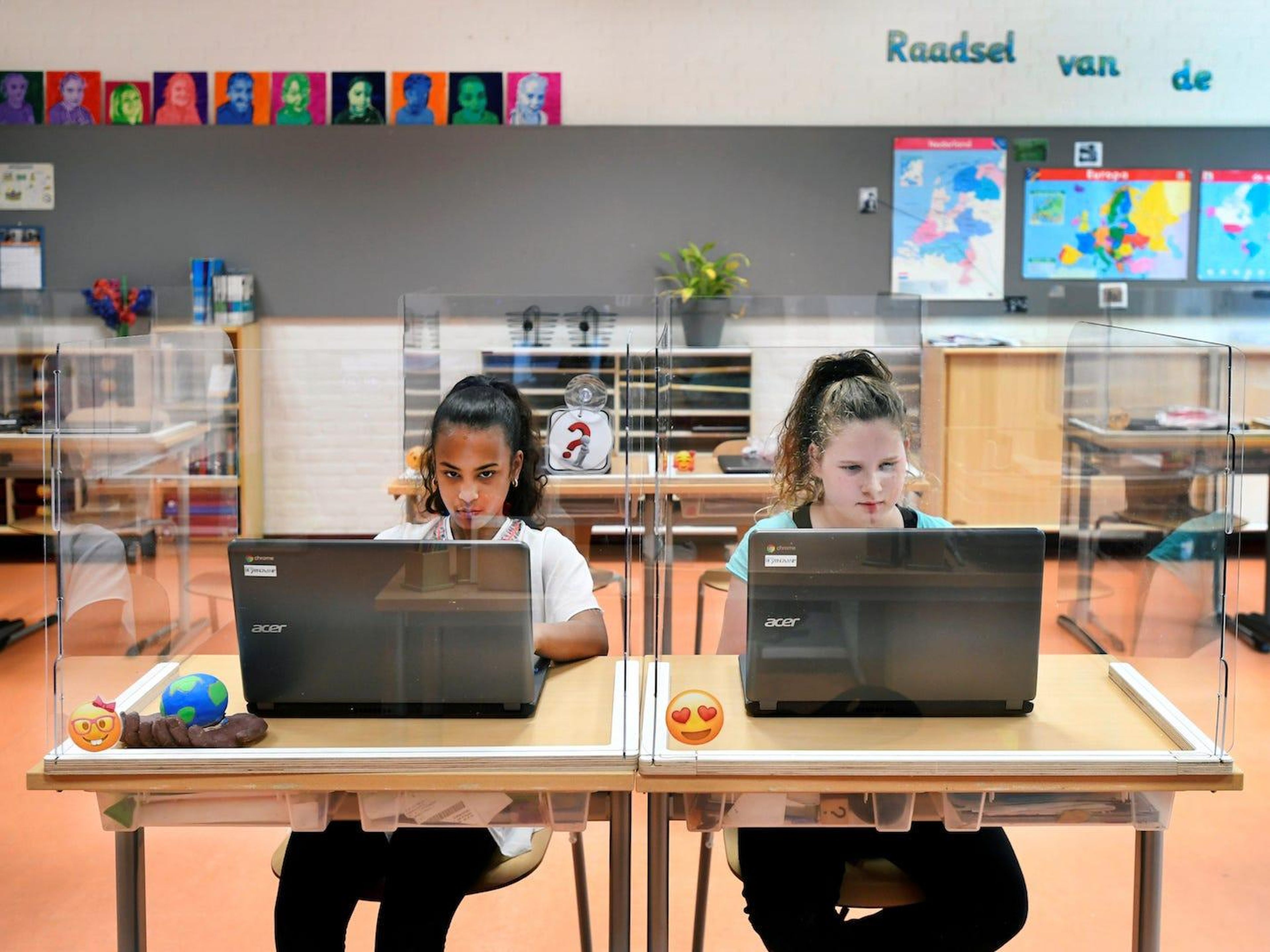 Alumnos sentados detrás de tableros de plexiglás asisten a clase en una escuela primaria en Den Bosch, Países Bajos, 8 de mayo de 2020.