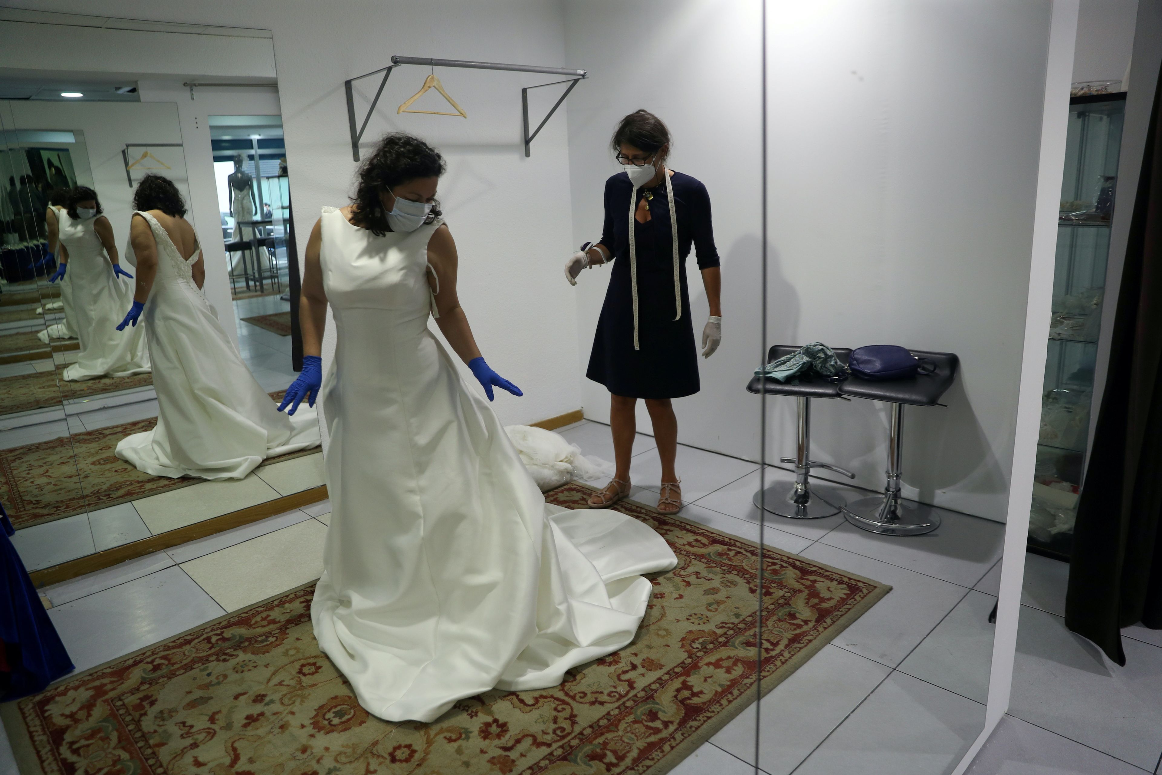 Una clienta y una empleada mantienen las medidas de seguridad en una tienda de vestidos de novia.