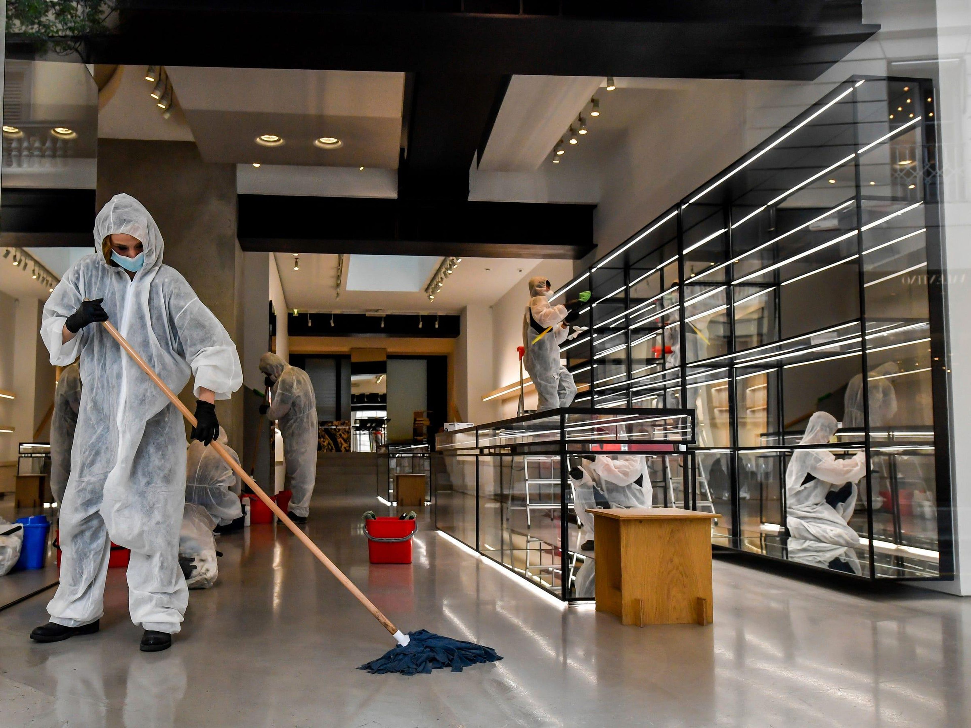 Trabajadores con trajes de protección desinfectan una tienda en la calle comercial de moda Monte Napoleone, en Milán, Italia, el 27 de abril de 2020.