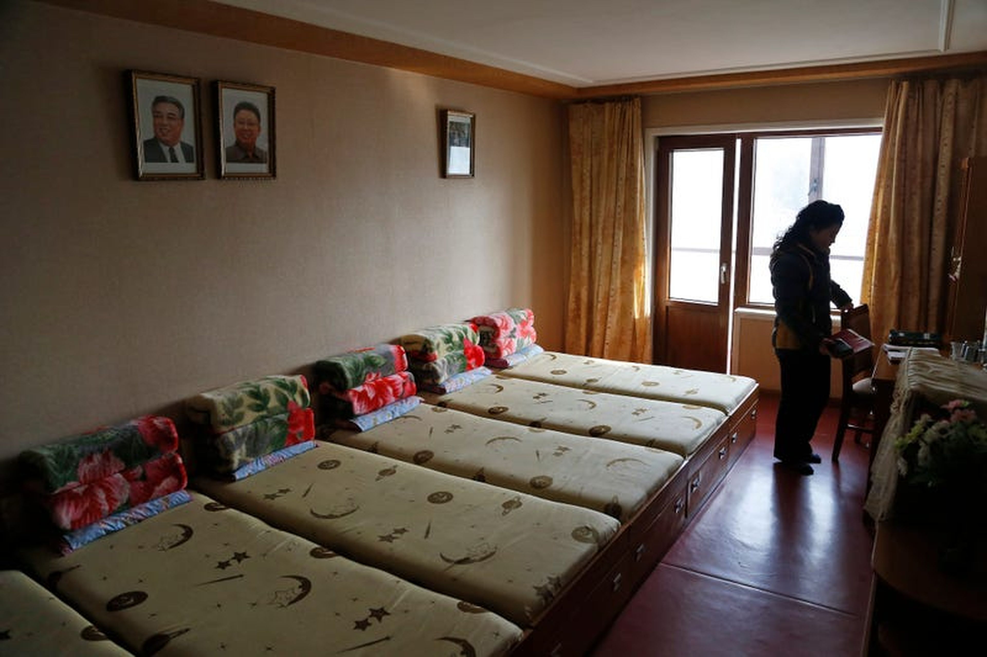 Un empleado se encuentra dentro de una habitación en un dormitorio provisto para trabajadores de fábricas textiles.