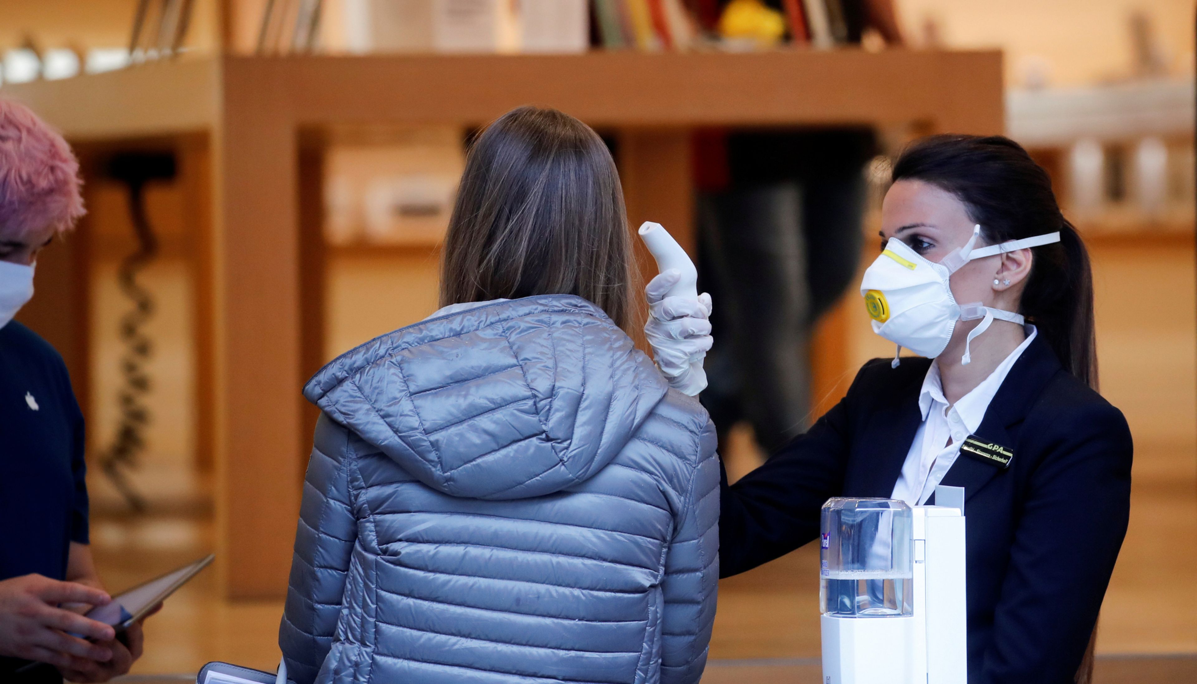 Una empleada de la Apple Store de Zurich (Suiza) mide la temperatura de una clienta