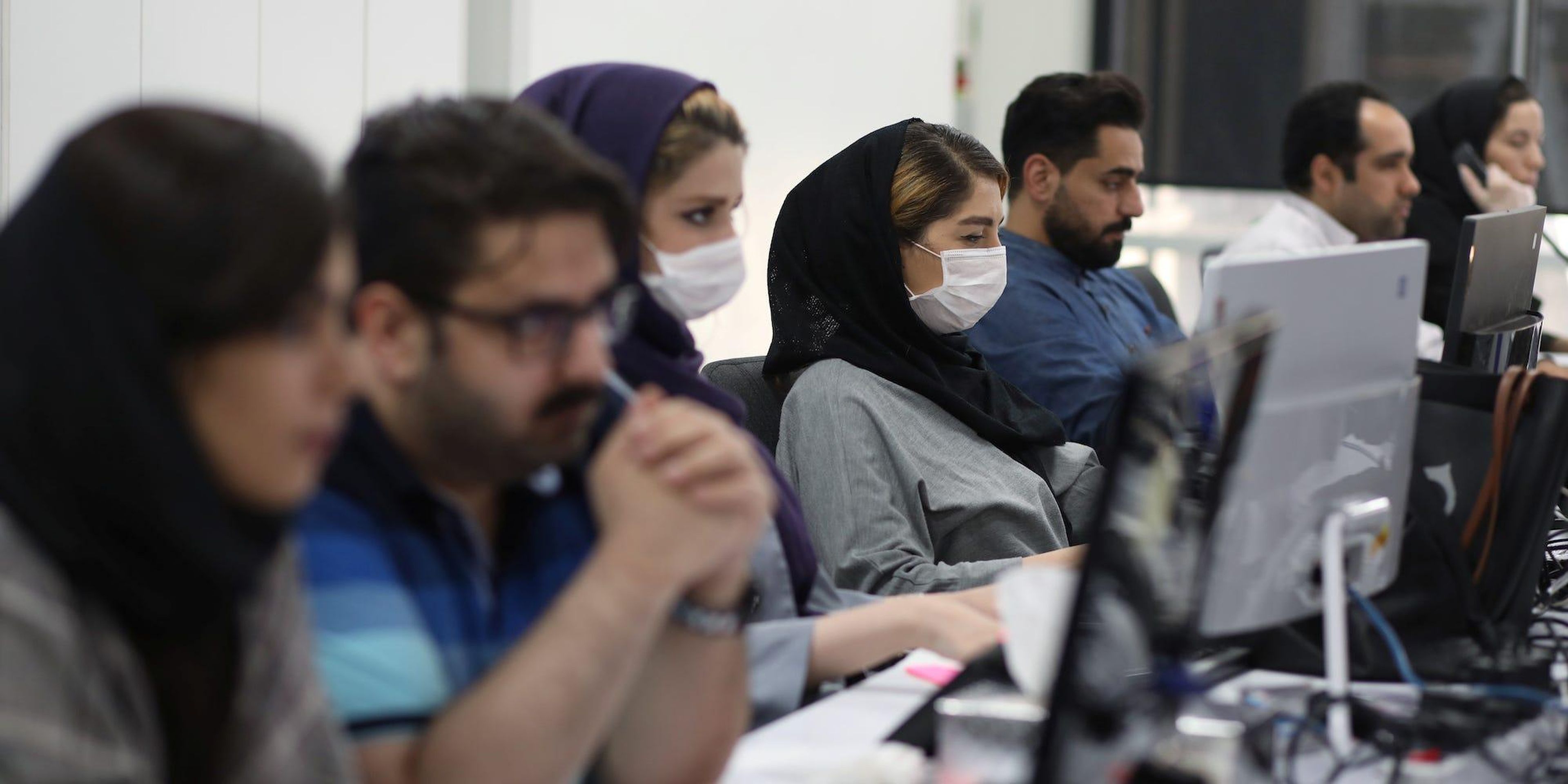 Empleados de una firma de agentes de bolsa vigilan los precios de las acciones en Teherán, Irán, el 12 de mayo de 2020.