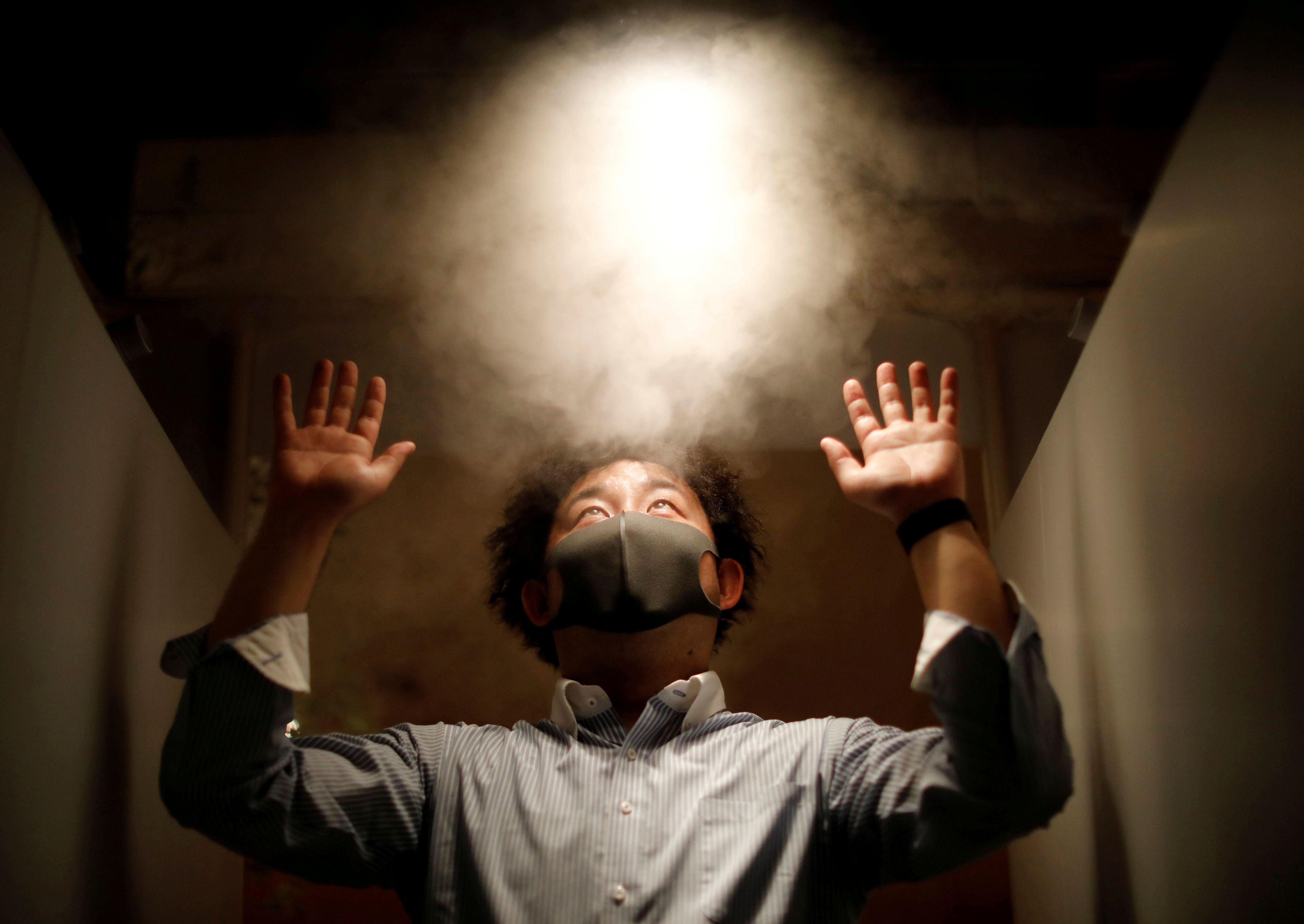 Un hombre es rociado con agua con ácido hipocloroso como medida para prevenir el contagio del coronavirus en Tokio