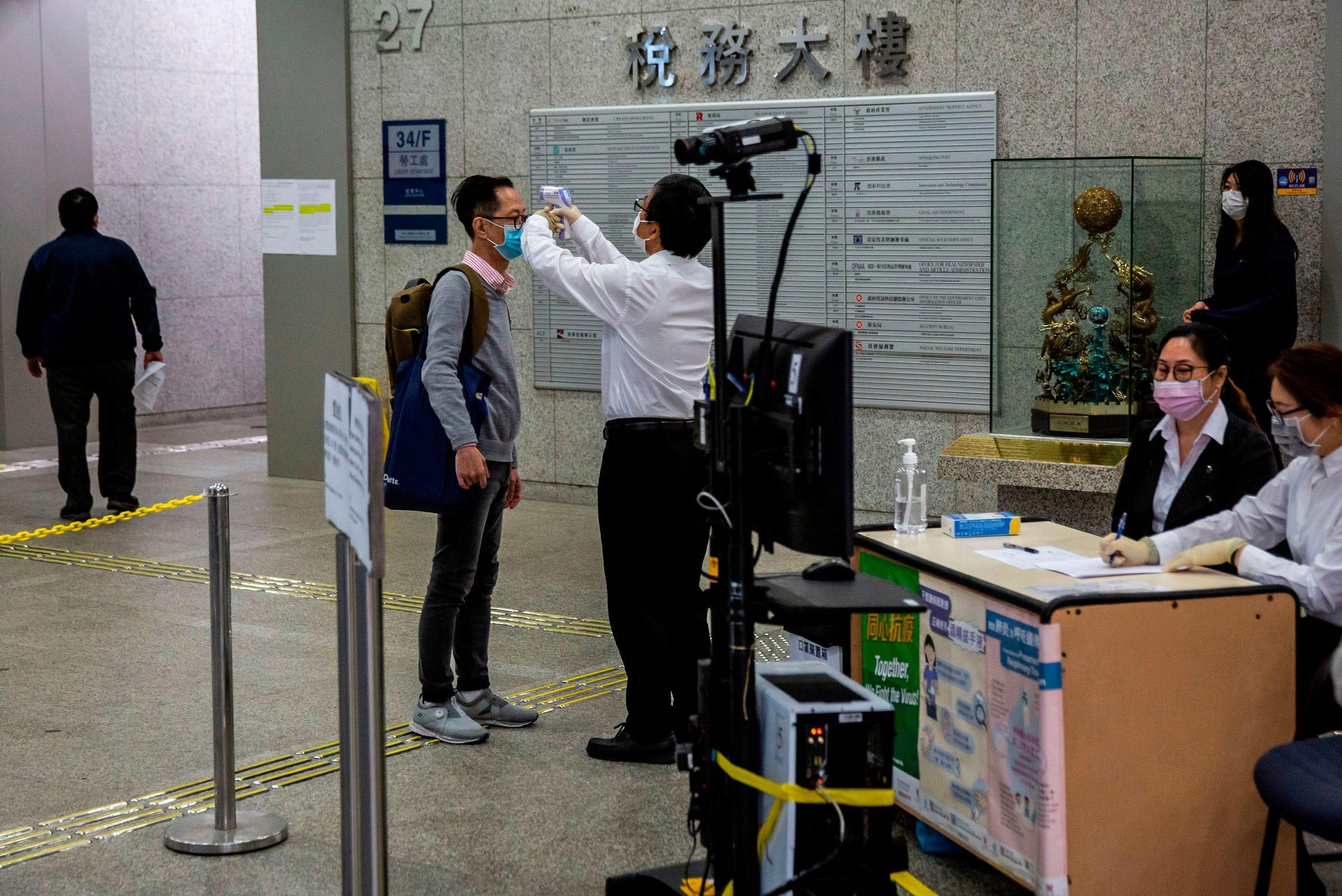 Se controla la temperatura de un hombre antes de ingresar a un edificio de oficinas gubernamentales en Hong Kong el 2 de marzo de 2020