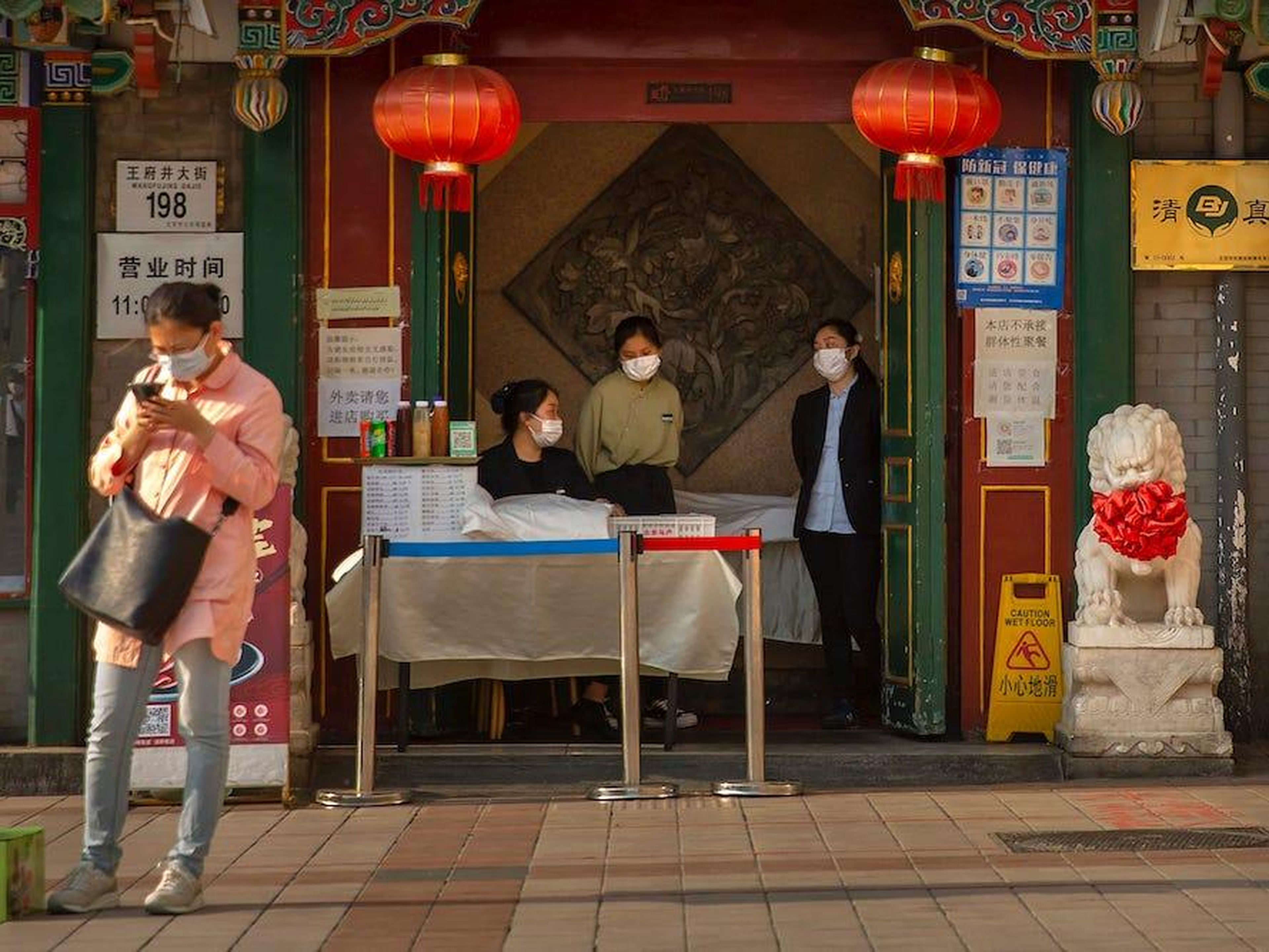 Los empleados usan mascarillas para evitar la propagación del virus mientras esperan a los clientes en la entrada de un restaurante en Beijing, el martes 28 de abril de 2020.