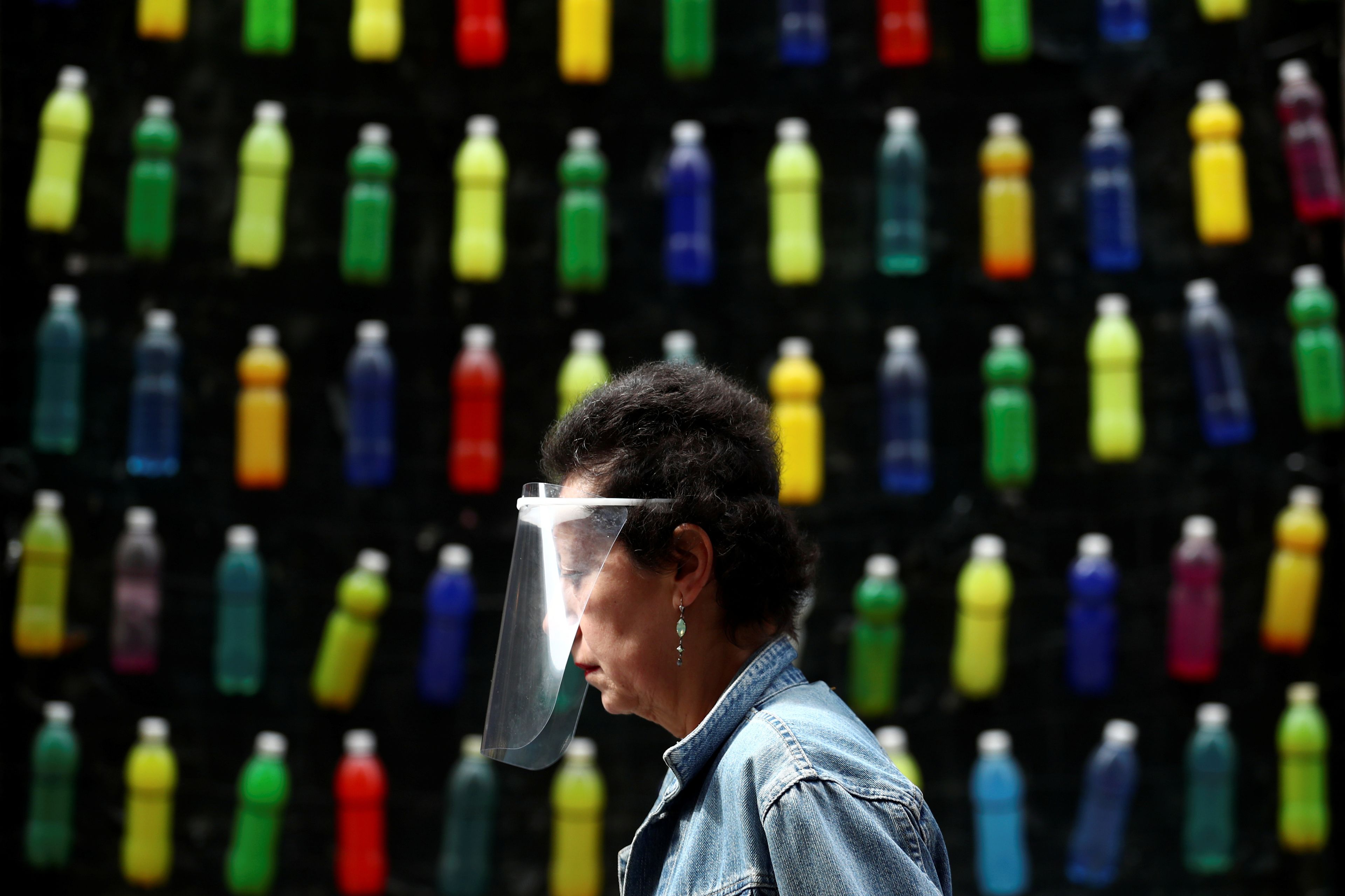 Una mujer pasea por Madrid con una pantalla facial para protegerse del coronavirus.
