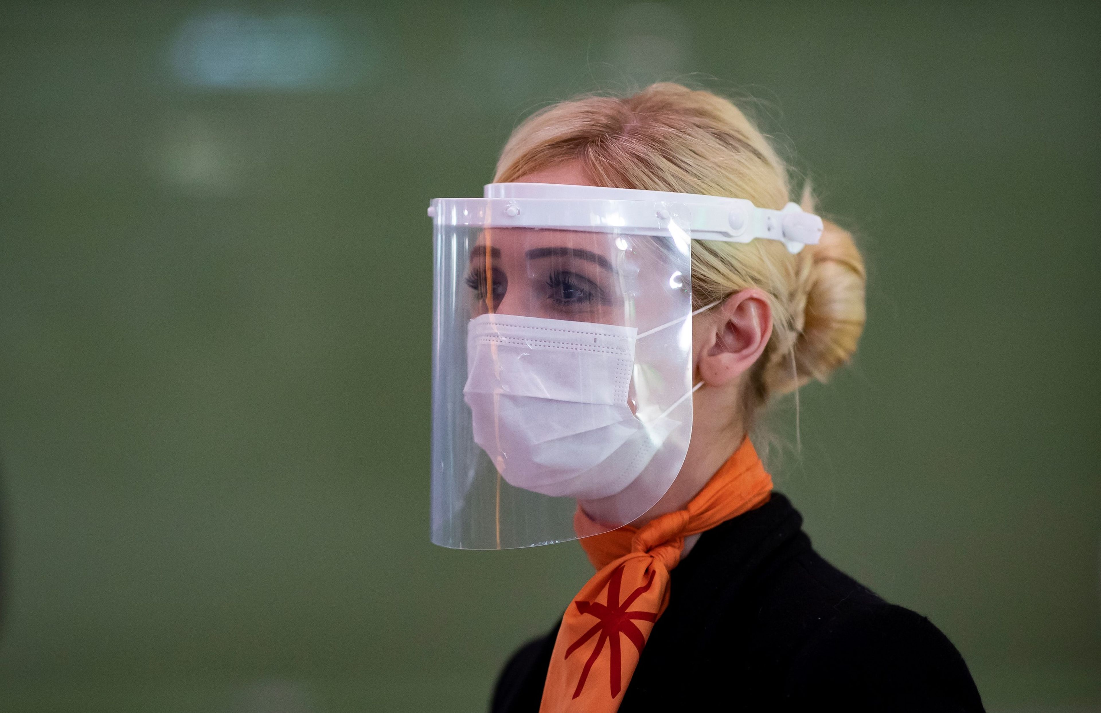 Una mujer se protege con una pantalla facial en un aeropuerto en medio de la pandemia del coronavirus