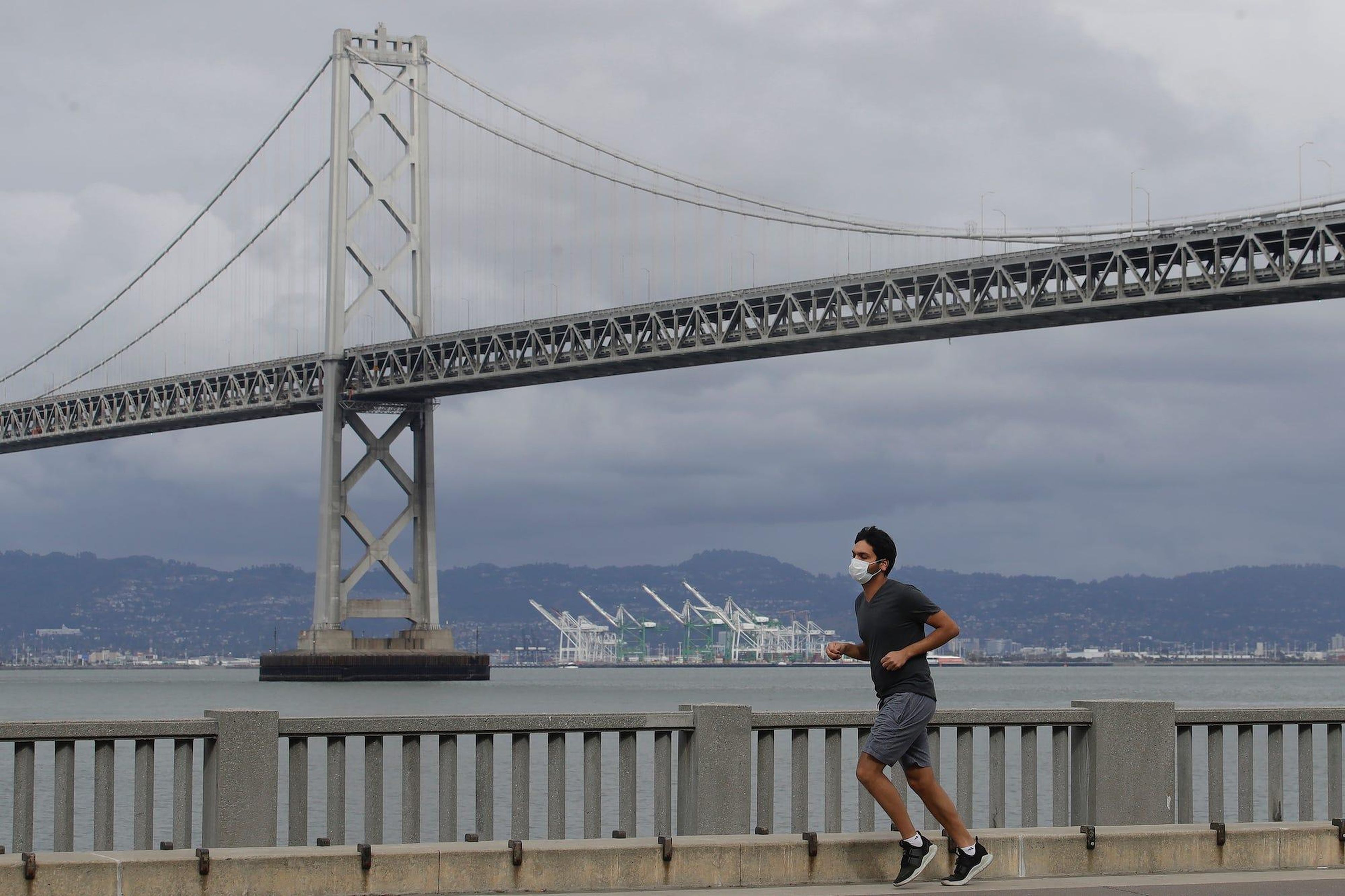 Un hombre con mascarilla corre por el Embarcadero en San Francisco.
