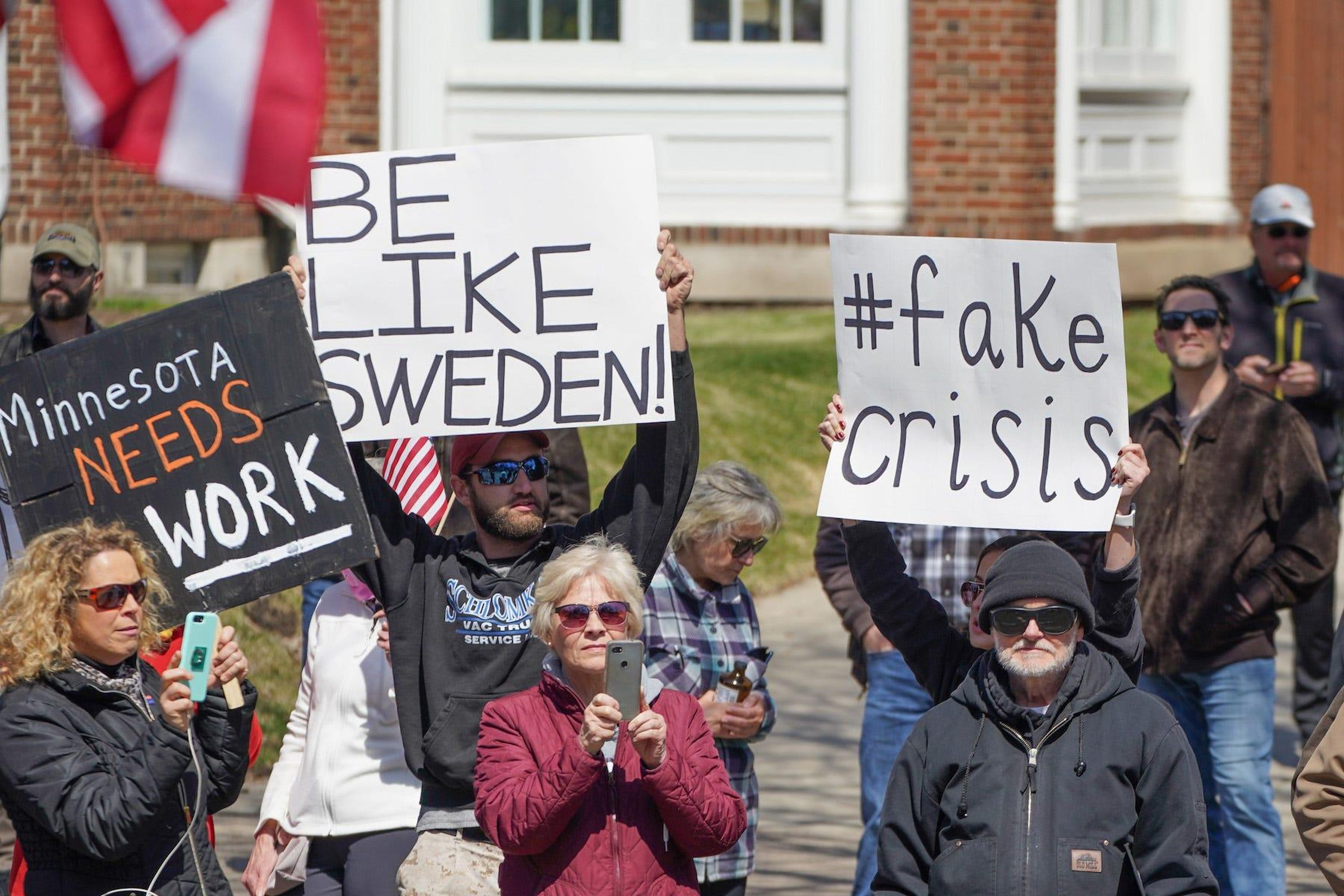 La gente protesta contra la orden de quedarse en casa de Minnesota con un letrero de "Sé como Suecia" frente a la residencia del gobernador el 17 de abril de 2020.